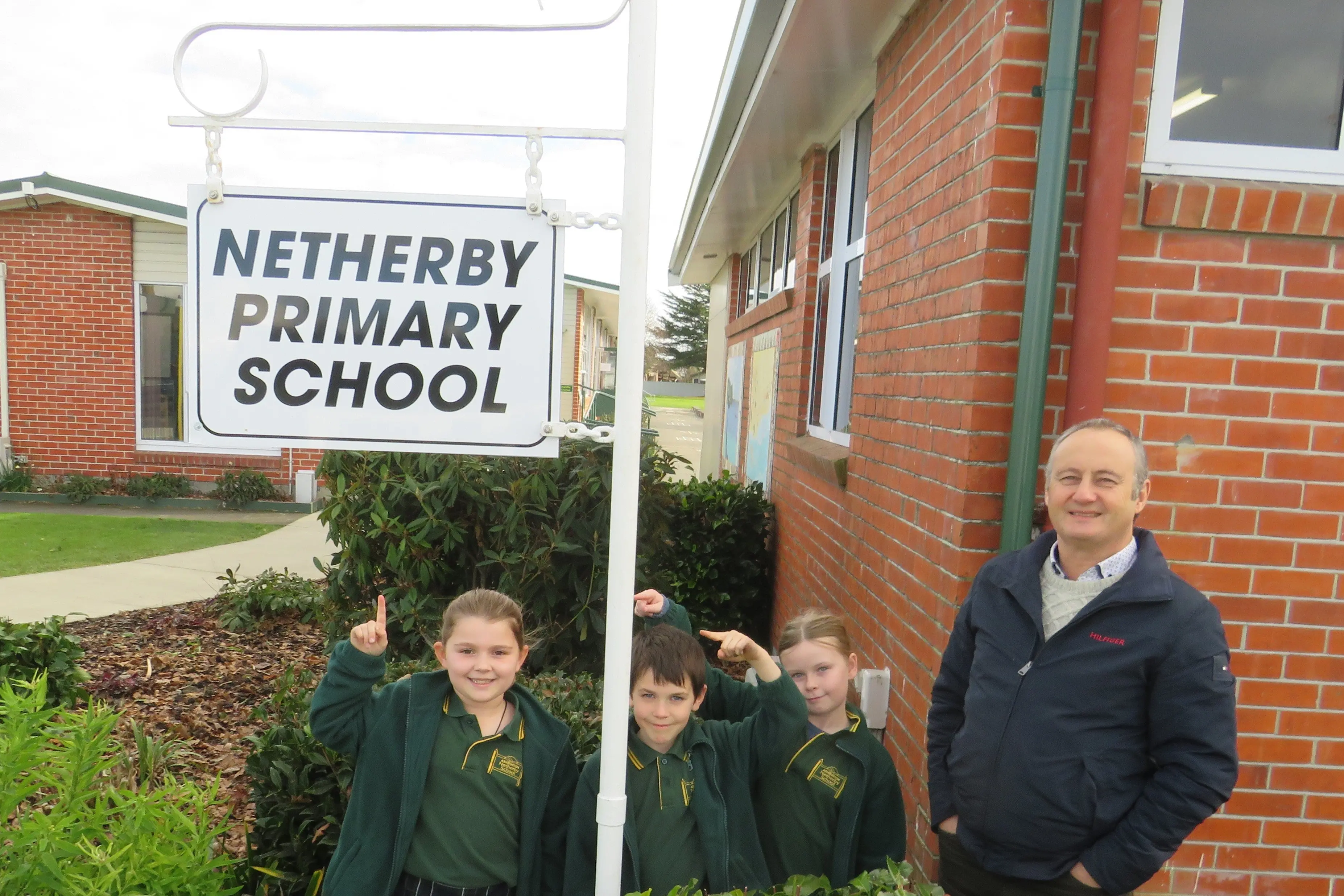 Ashburton Netherby School pupils, from left, Eve Boleyn, 8, Isaac Mason, 7, and Peyton Bradford, 7, with principal Phil Wheeler and, what is believed to be, the original school sign now back at the front gate thanks to a series of uncanny coincidences. Photo: Heather Mackenzie