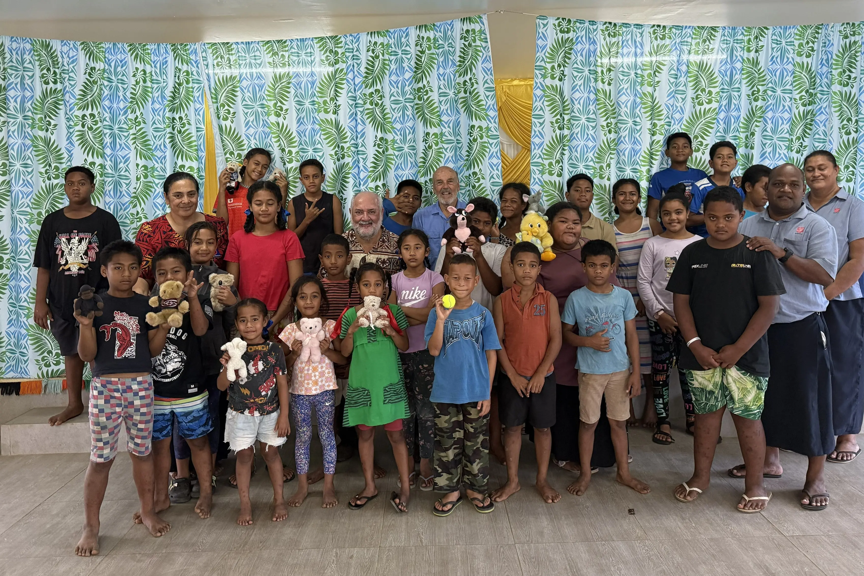 Children in the Salvation Army Children\\'s programme with donated toys at the new Atata Village in Tonga. Present are Pasifika Safe Shelter Trust president Peter Rodwell and managing director Jim Grieve (centre) and Salvation Army leader (left) Sesilina Palu.
