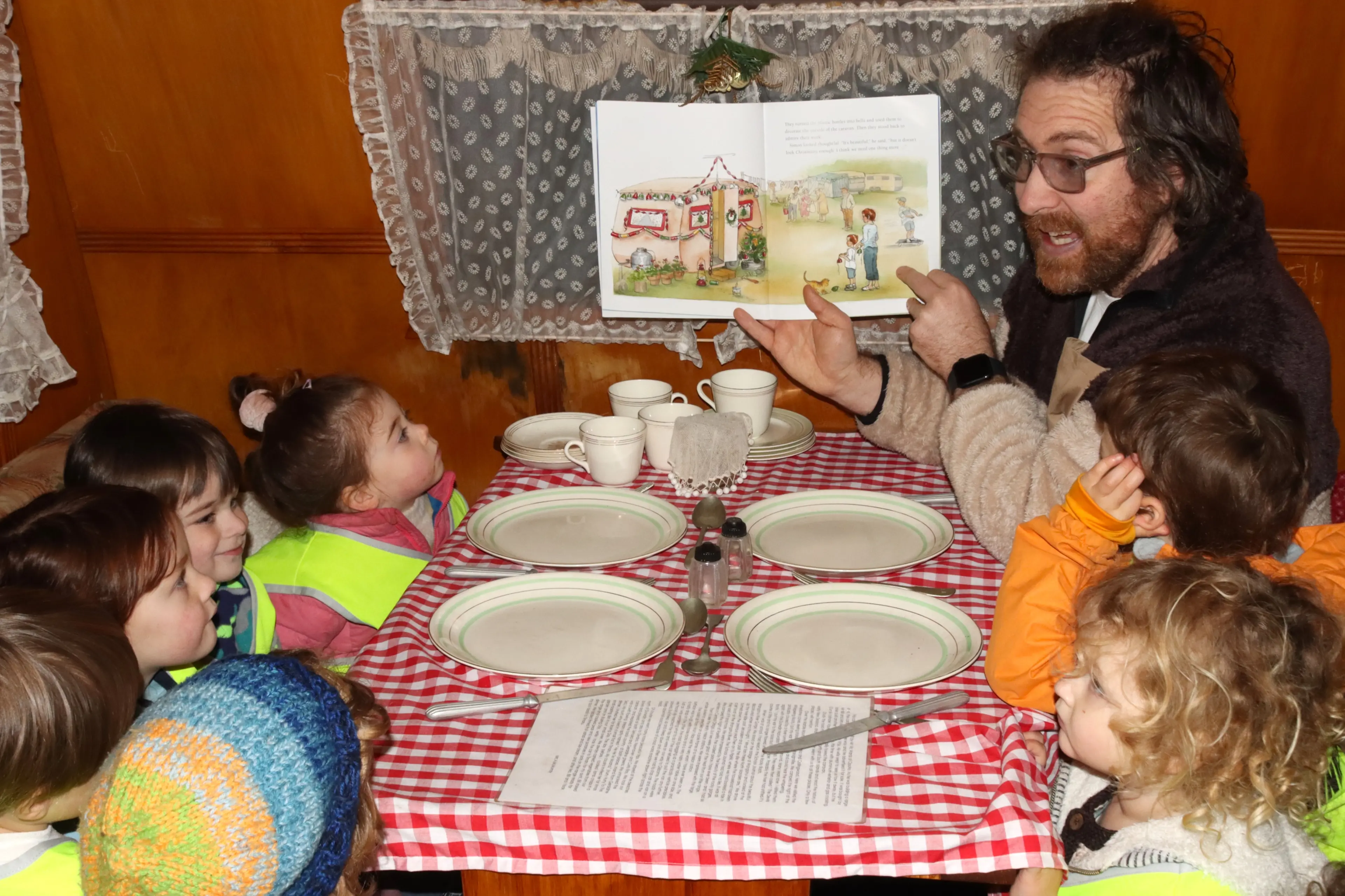 Portobello Kindergarten head teacher Nathan Pollock reads \\'The Christmas Caravan\\' to children inside the actual caravan that inspired the story. Photo: Sam Henderson