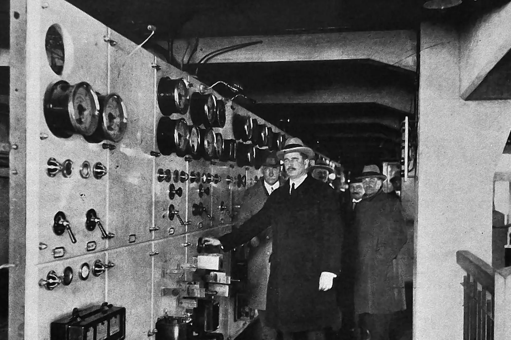 Prime minister Gordon Coates throws a switch in the control room to turn on new pipelines feeding new generators at Lake Coleridge hydro-electric power station, in Canterbury. Photo: <i>Otago Witness</i>, issue 3799, August 17, 1926, page 45