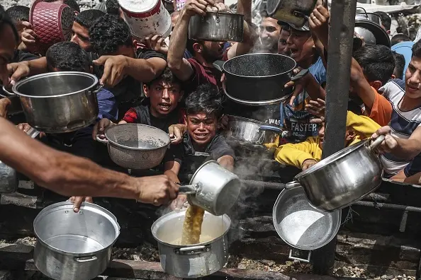 Hungry Palestinians wait to receive meals distributed by charity organisation in Jabalia Refugee Camp, Gaza City.  Photo: Getty Images 