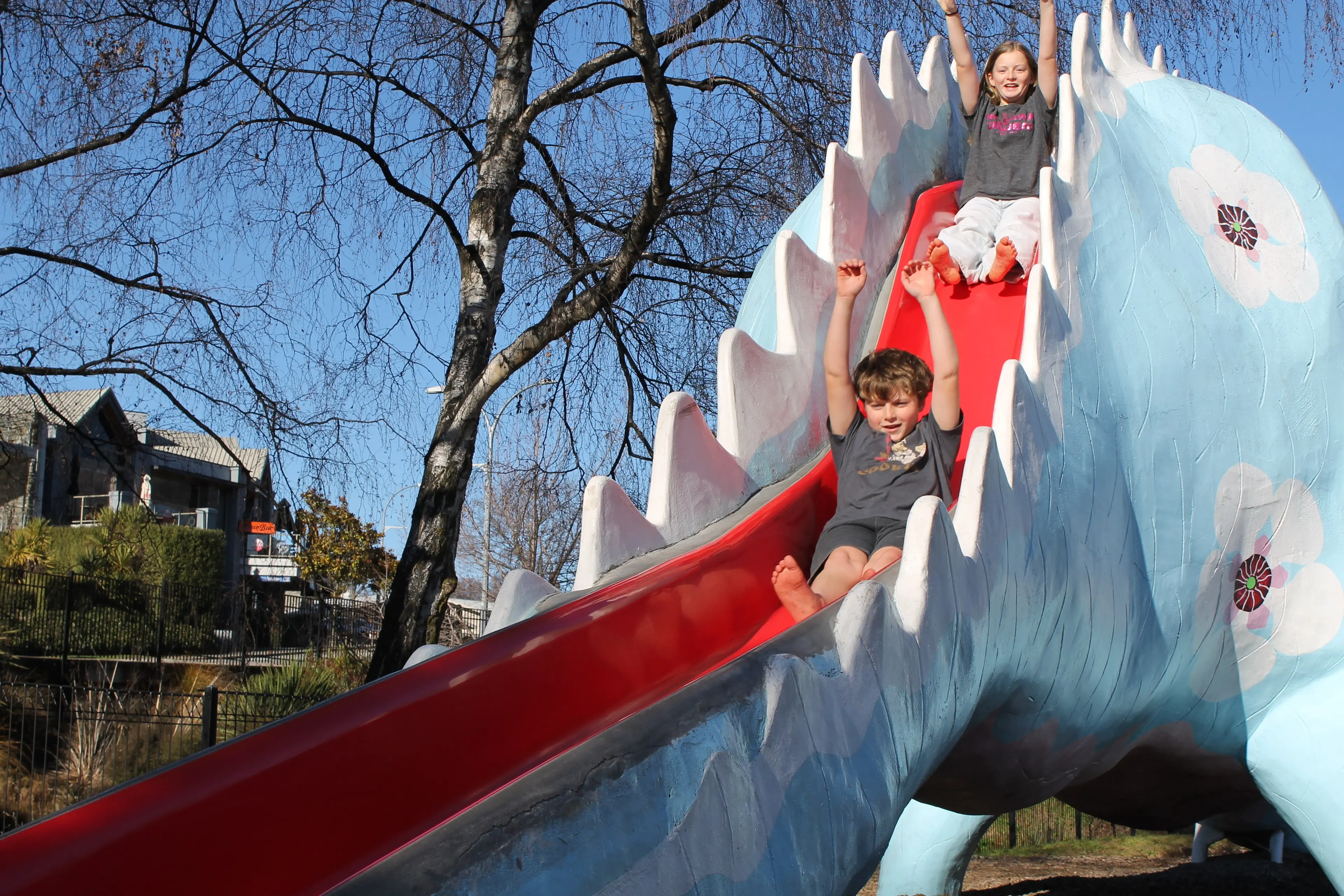 Siblings James, 10, and Harriet Taylor, 12, of Hawke\\'s Bay, go for a ride down the W\\u0101naka dinosaur slide as it celebrates 50 years. Photo: Evie Sinclair