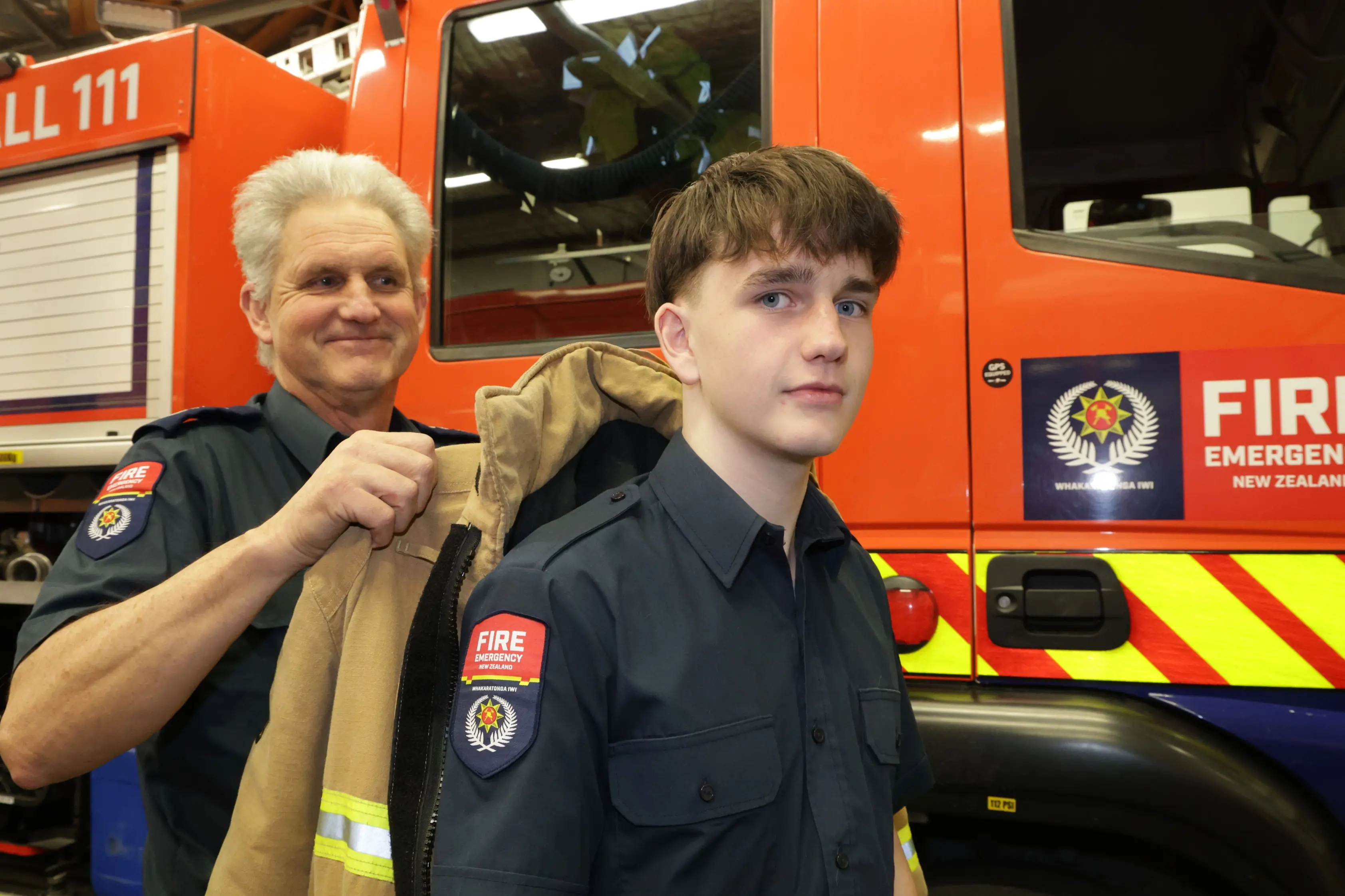 Together and proud. . . Woodend Chief Fire Officer Shayne Robinson helps his son Isaac (16) to get dressed in his protective gear during a training night at the Woodend Volunteer Fire Brigade. Photo: John Cosgrove