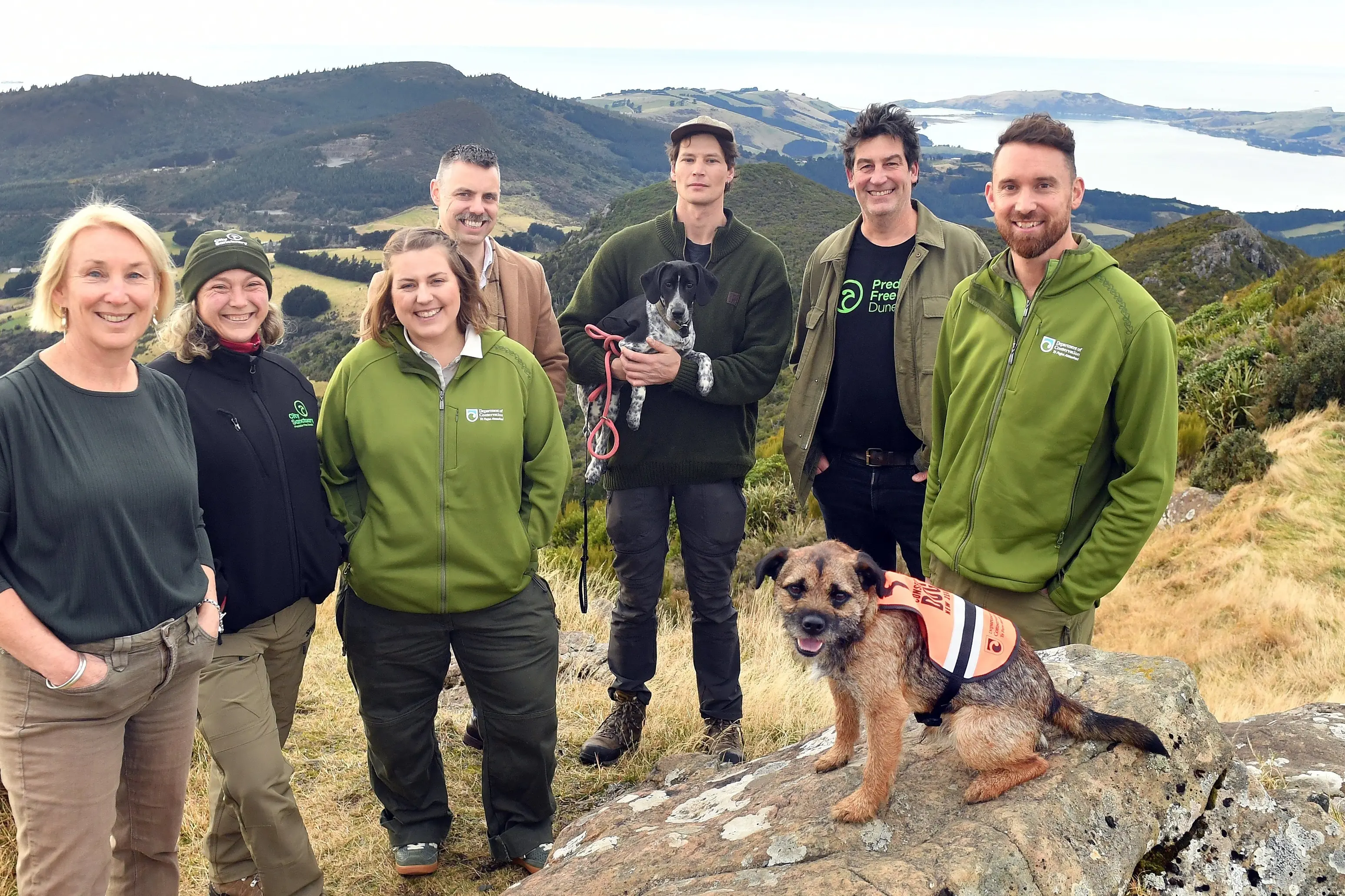Welcoming a $3.9 million investment in Predator Free Dunedin by the Department of Conservation (from left) Predator Free Dunedin chairwoman Sally Peart, City Sanctuary project manager Kate Tanner, Doc coastal Otago district principal ranger Sam Marsh, Dunedin City Council group manager parks and recreation Heath Ellis, The Halo Project predator free project manager Jonah Kitto-Verhoef (holding trainee mustelid scat detector dog Pepper), Predator Free Dunedin The Halo Project lead Rhys Millar, Doc coastal Otago district operations manager Gabe Davies; (front) possum scat detection dog Scout. Photo: Stephen Jaquiery