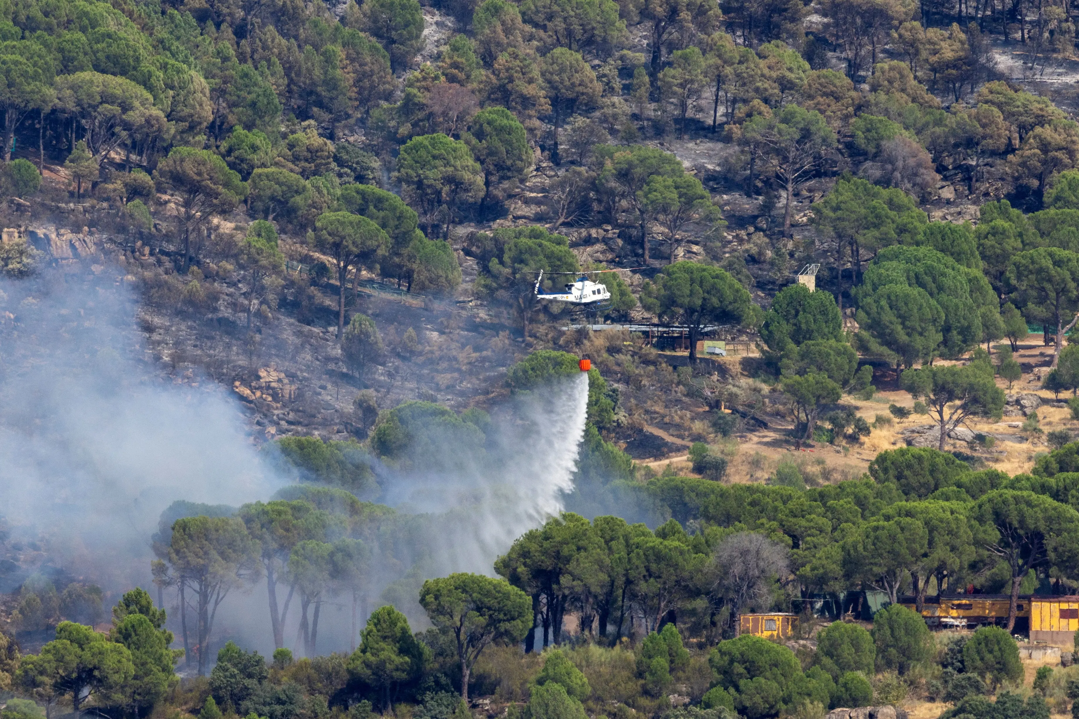 A firefighting helicopter drops water near El Tiemblo during a wildfire in Avila province, Spain. Photo: Reuters