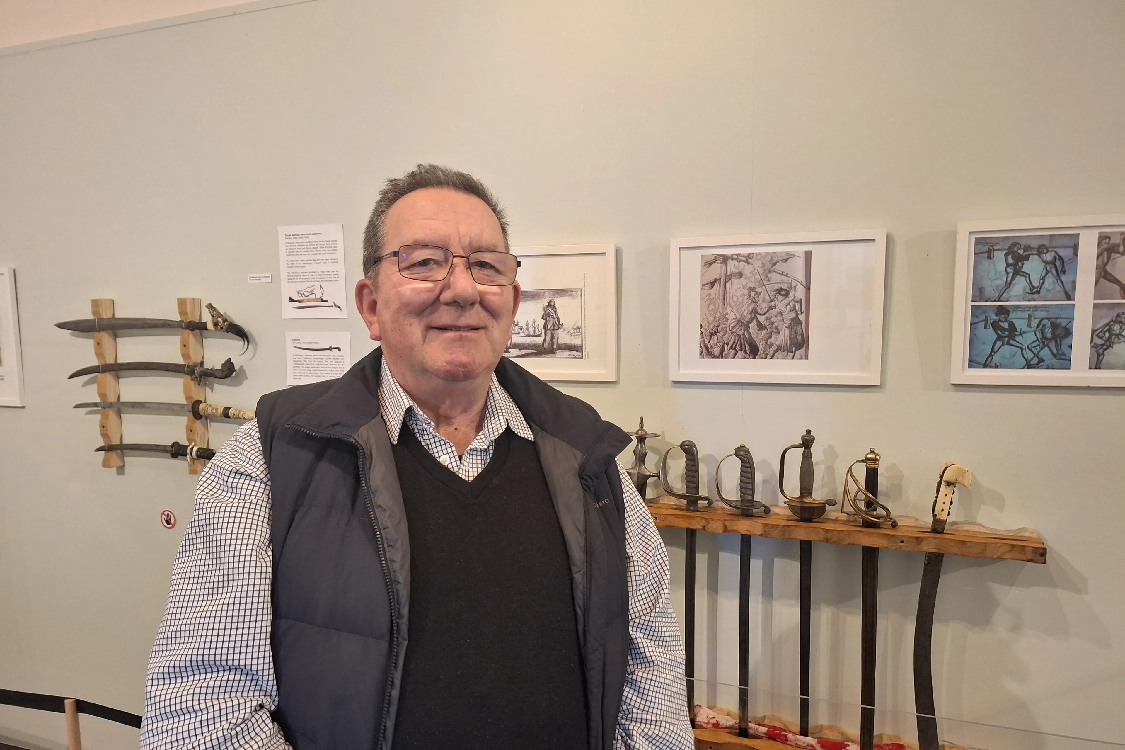 Riverton\\'s Te Hikoi Museum trustee Stephen Bradshaw stands in front of a collection of swords that are part of the weapons exhibition at the museum. Photo: Supplied