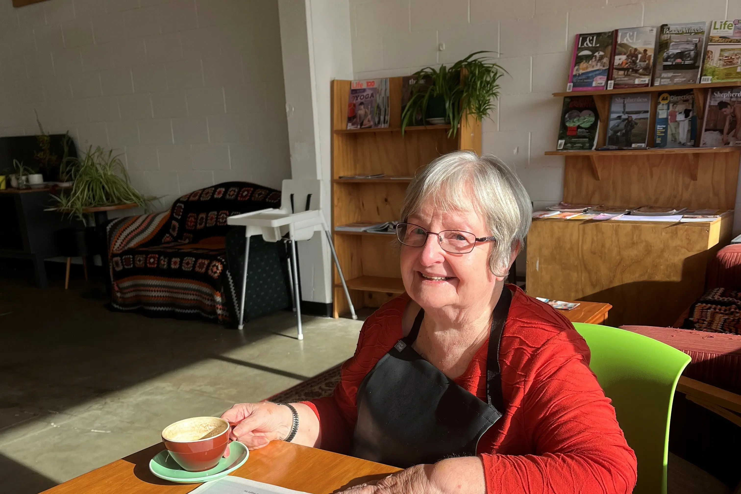 The Pod Cafe volunteer Lynda Kennedy takes time out from her duties to enjoy a cup of coffee and a read of the Southland Express. Photo: Supplied