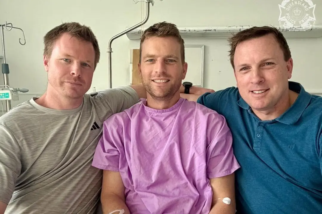 Constable Jordan May (centre) with his brothers at Royal Brisbane Hospital after being shot in the line of duty on Friday, July 24.