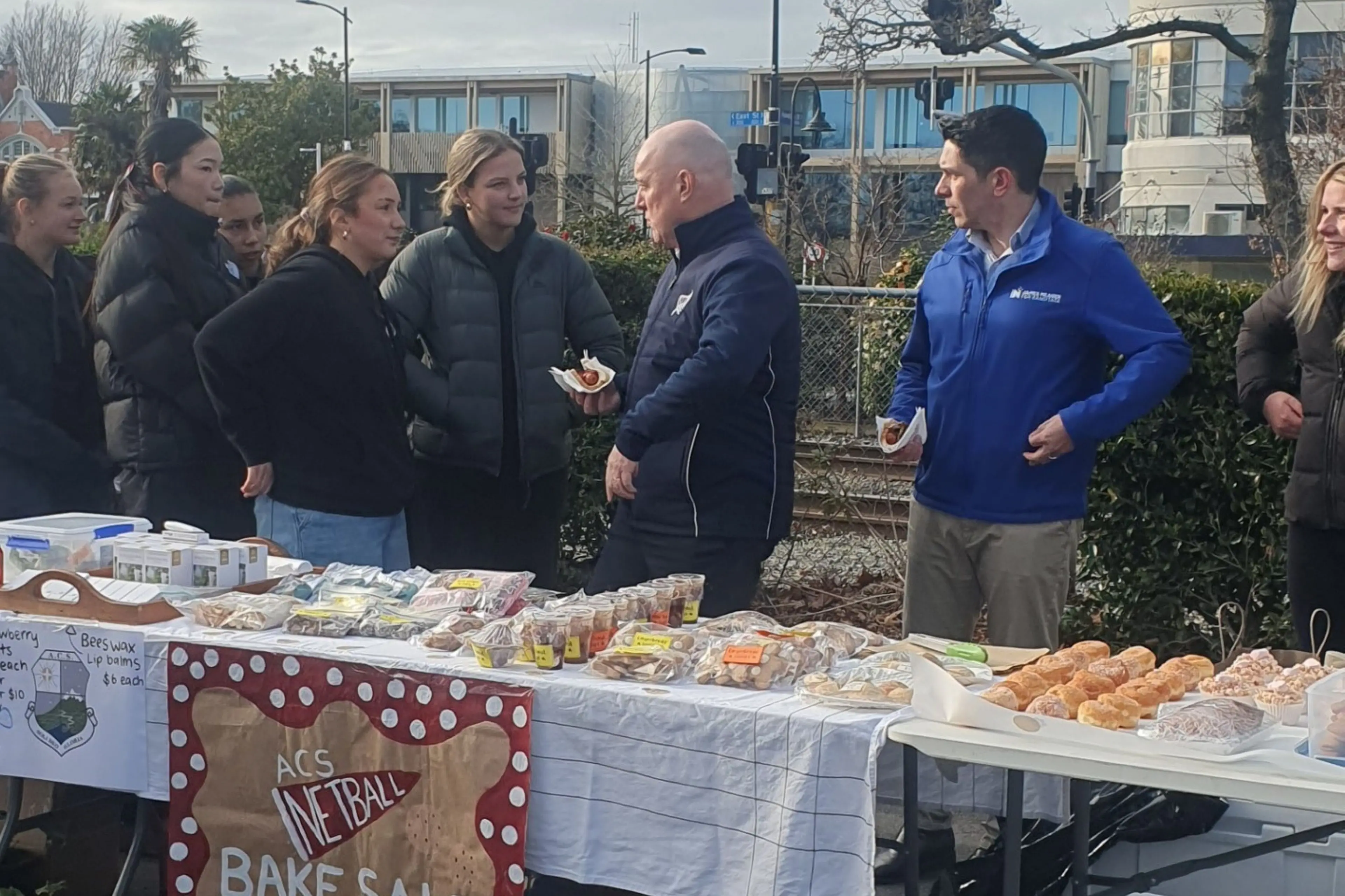 Prime Minister Christopher Luxon and Rangitata MP James Meagre visited the Ashburton Farmers\\u2019 Market, where they met Ashburton Christian School netballers at their fundraising table. Photo: Mary Summerfield