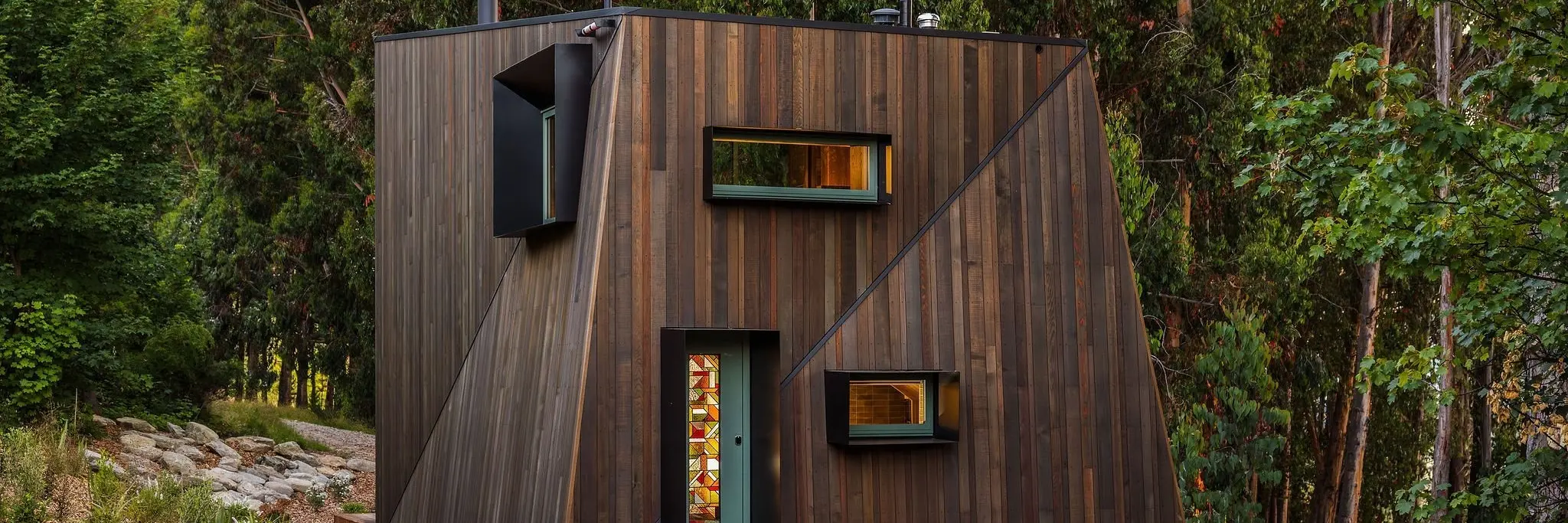 Set within a forest glade, this cabin features clever angles and a bridge-like entry deck. Photos: ImageWorks