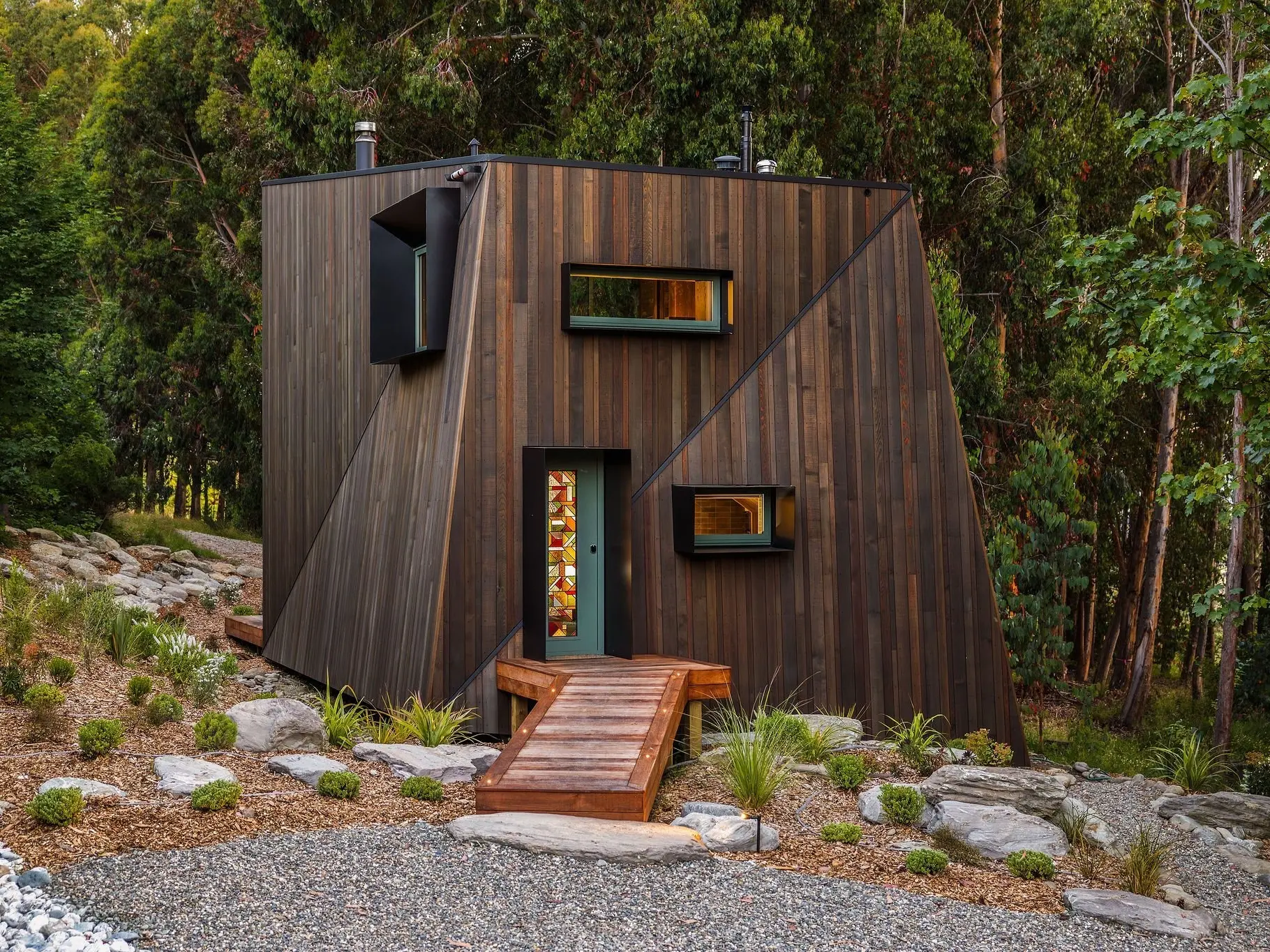 Set within a forest glade, this cabin features clever angles and a bridge-like entry deck. Photos: ImageWorks