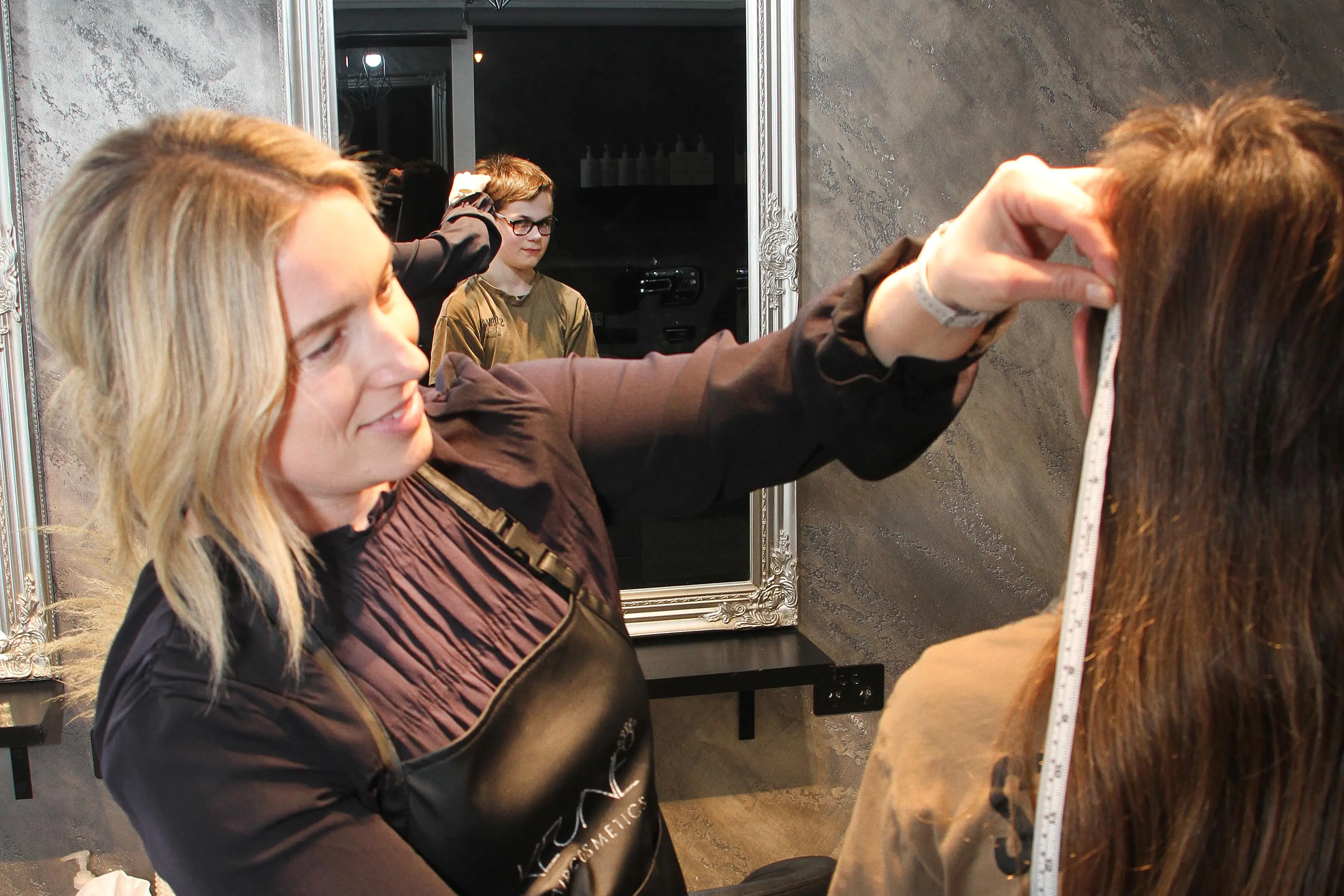 Checking the length . . . Kirsty of \\u2018Lavish by Kirsty Lorraine\\u2019 hairdressing, measures the length of Mason Cattermole\\u2019s mullet hair prior to cutting it for him as he raises money for the Ronald McDonald House and a wig charity. Photo: John Cosgrove