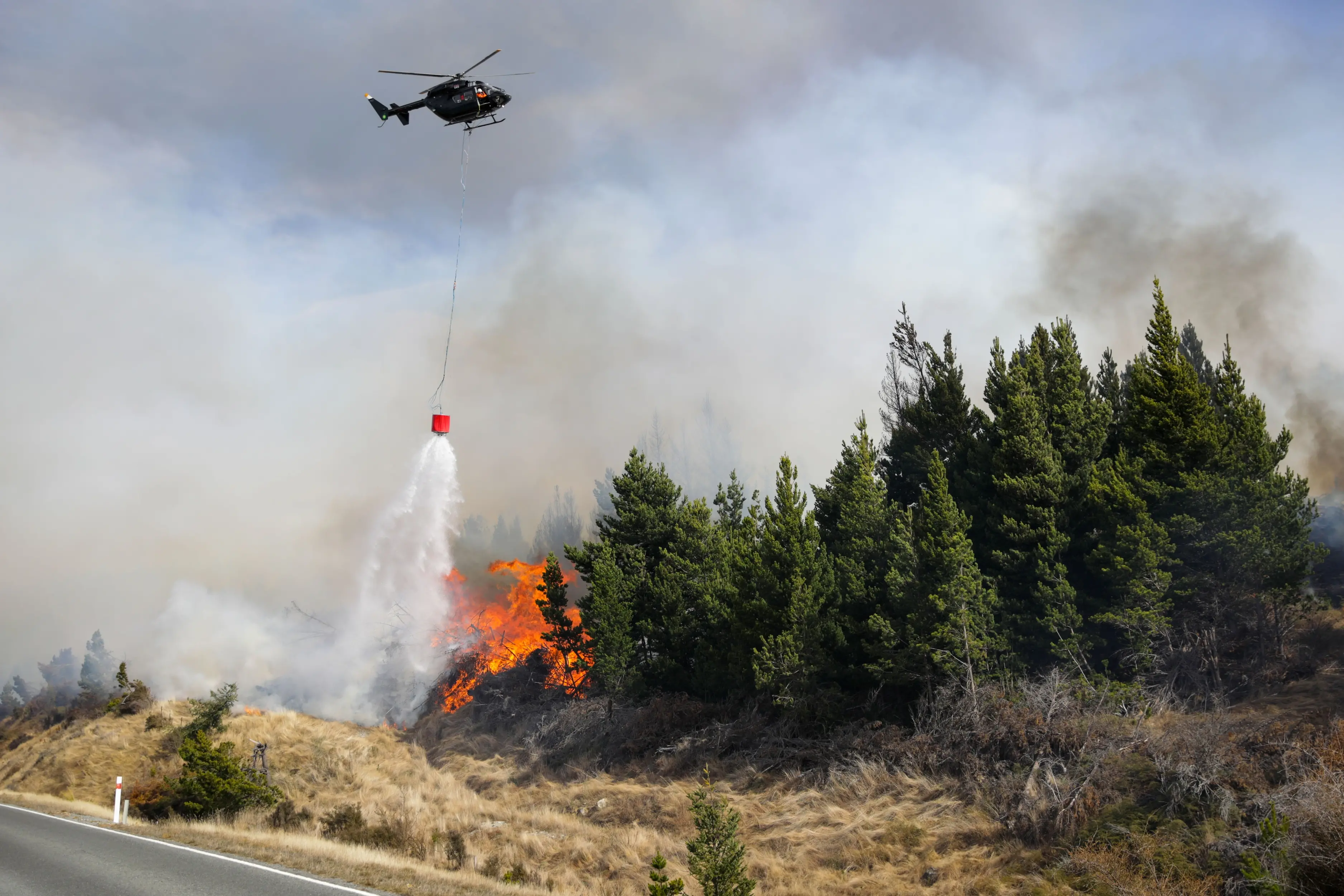 A helicopter drops water on a fire near Lake Pukaki in the Mackenzie Basin. Photo: RNZ (file)