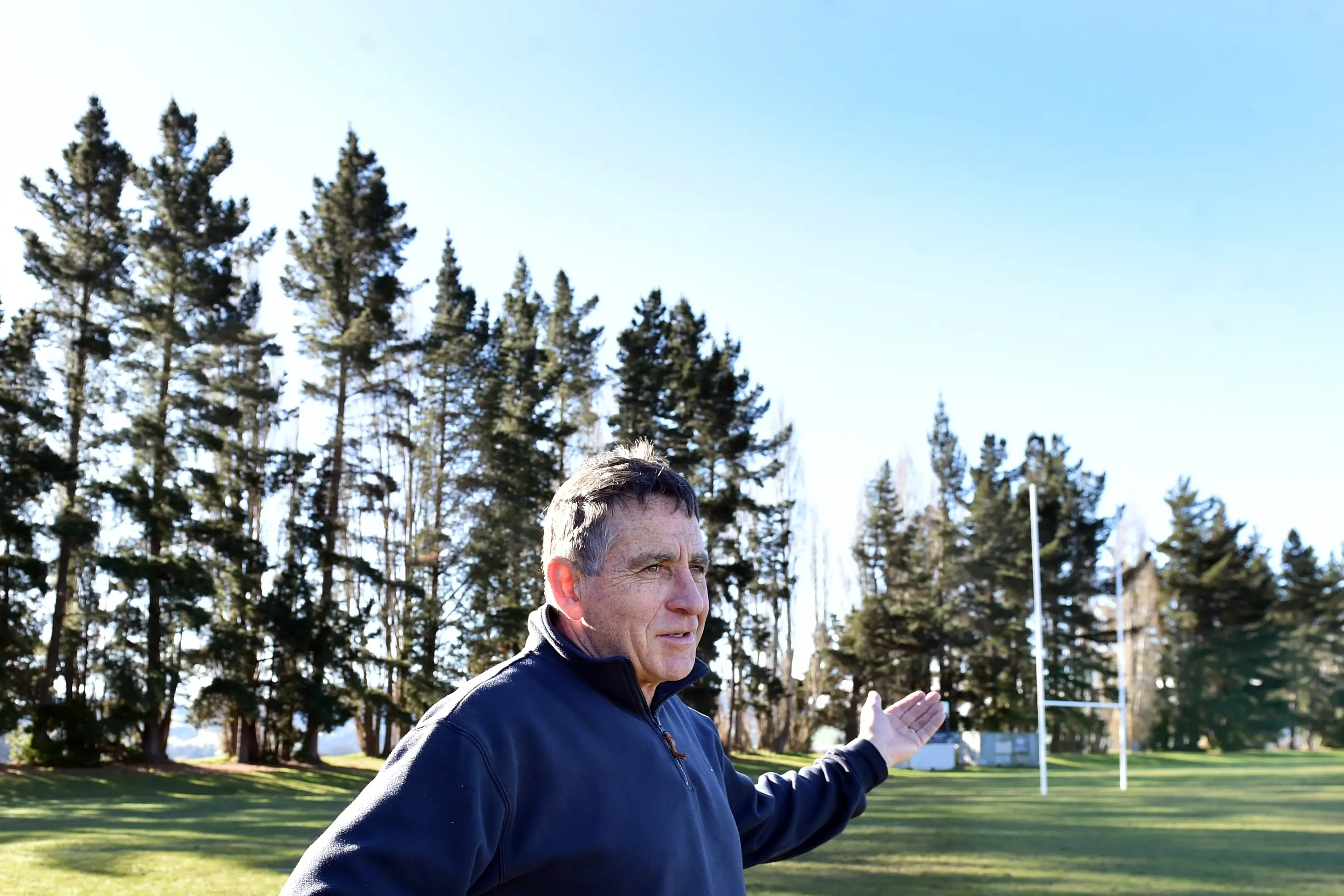 Taieri Rugby Football Club chairman Peter Dyer stands near a row of pine trees at Peter Johnstone Park, which he argues are unsafe and make drying the playing surface difficult. Photo: Peter McIntosh