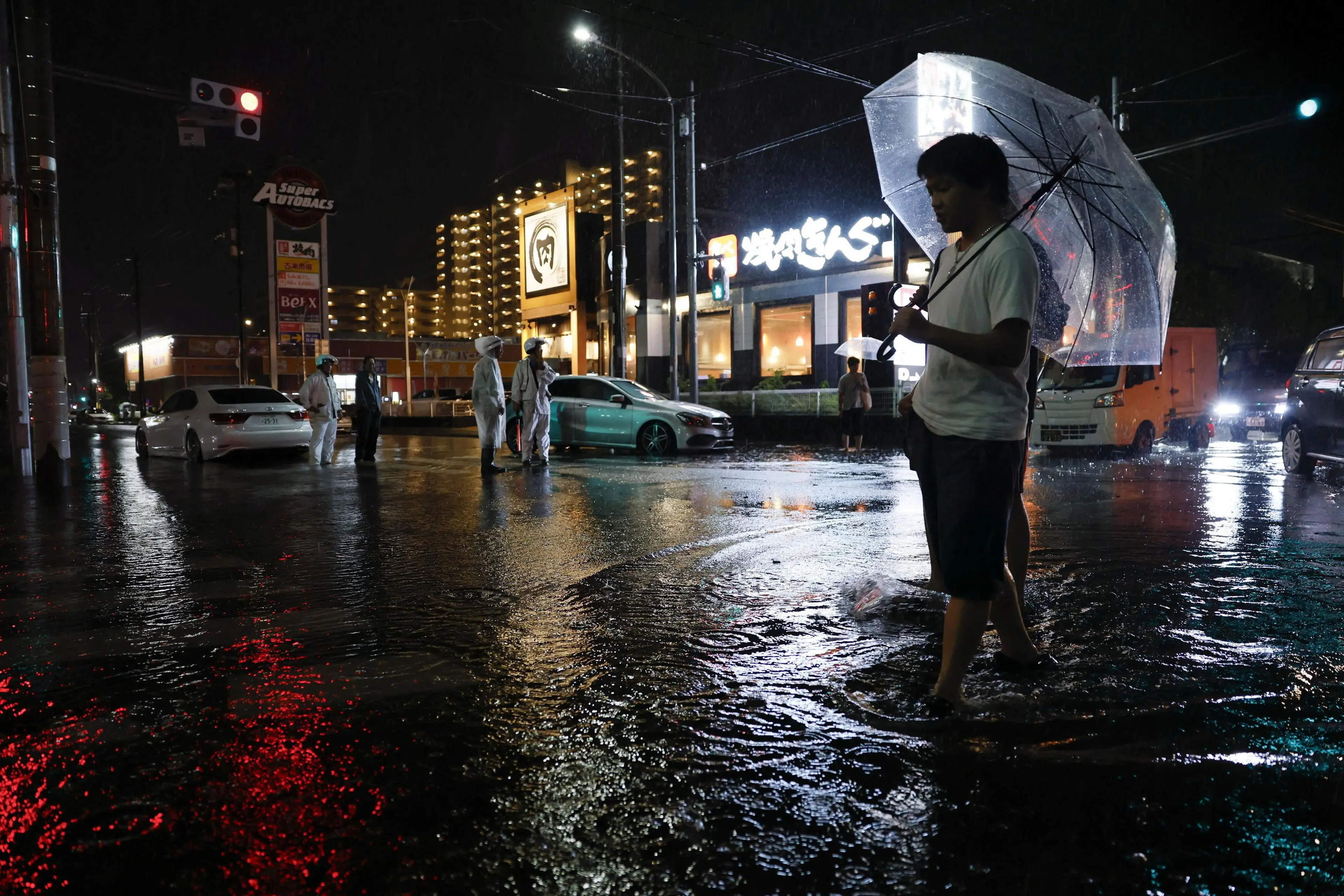 A man walks on a flooded road after torrential rain in Ichikawa, Chiba prefecture. Photo: Kyodo via Reuters