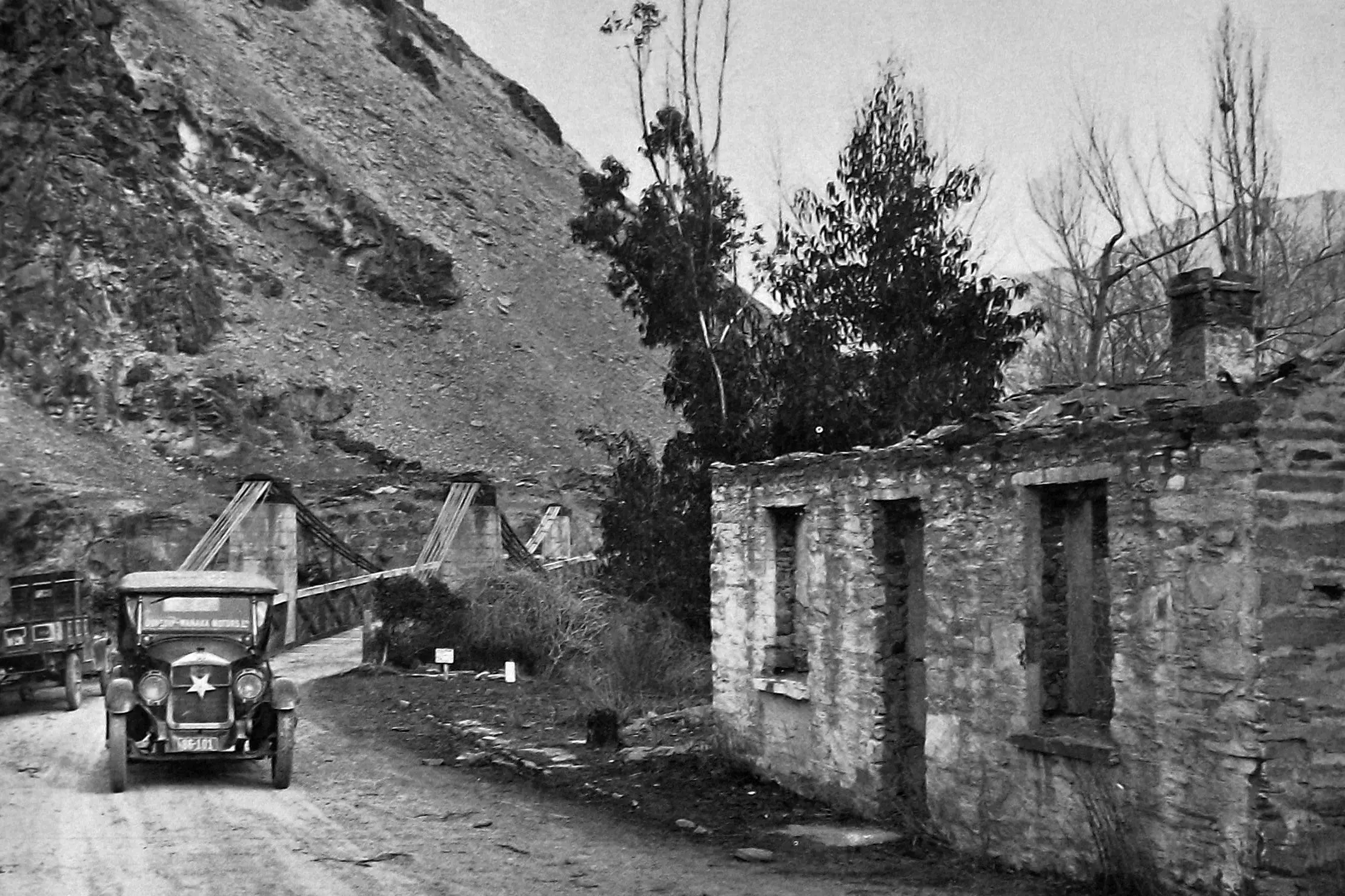 A White Star service car of Dunedin-Wanaka Motors crosses Victoria Bridge past ruins of a once famous hostelry in the Kawarau Gorge. Photo: <i>Otago Witness</i>, issue 3783, September 14, 1926, page 39