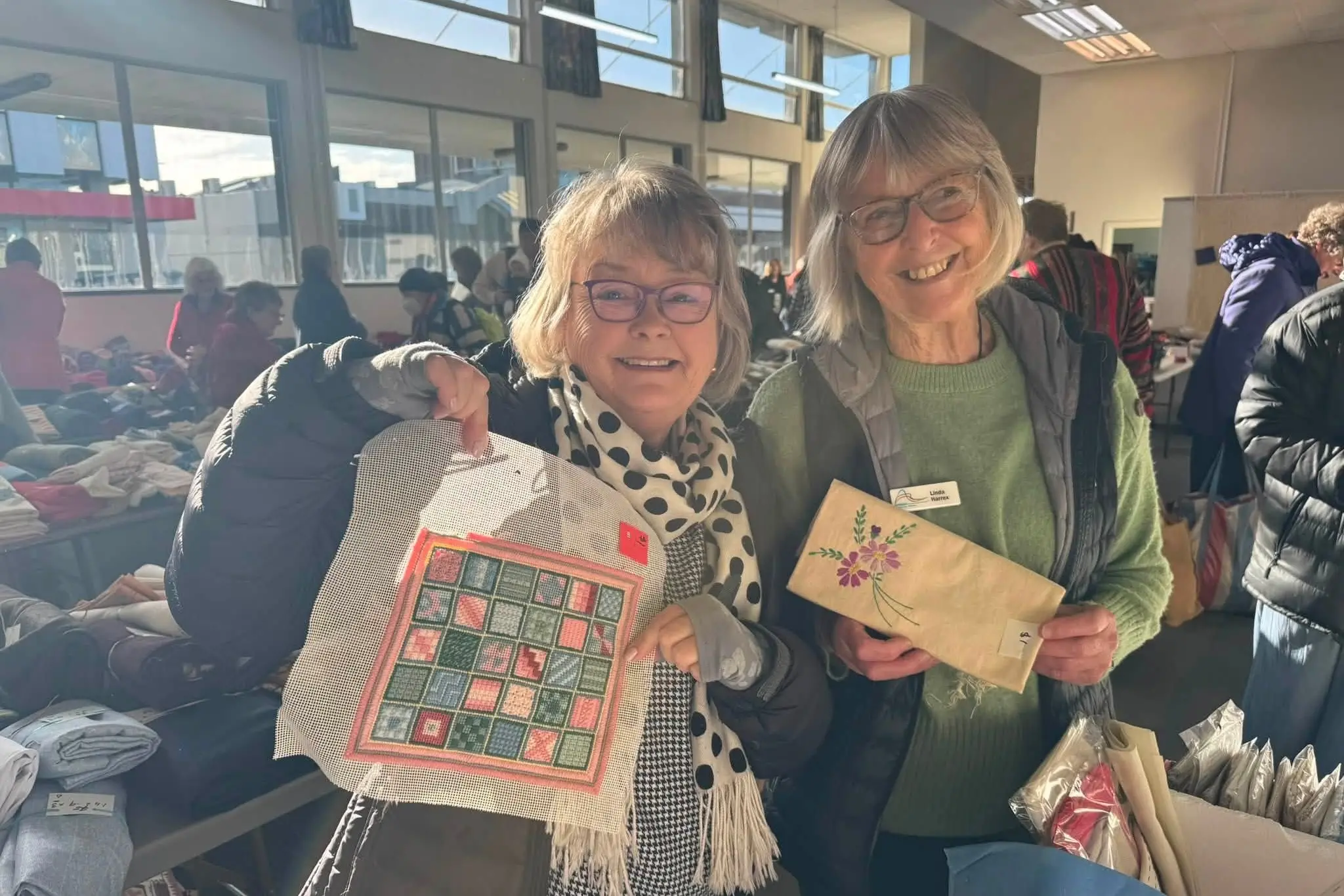 Altrusa members and volunteers, Shona McMillan and Linda Harrex, hold up fabric samples at the bazaar. Photo: Supplied