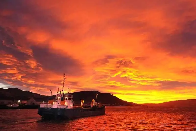 The Port Otago dredge \"New Era\" heads out of the upper harbour into a fiery sunrise. Photo: Stephen Jaquiery