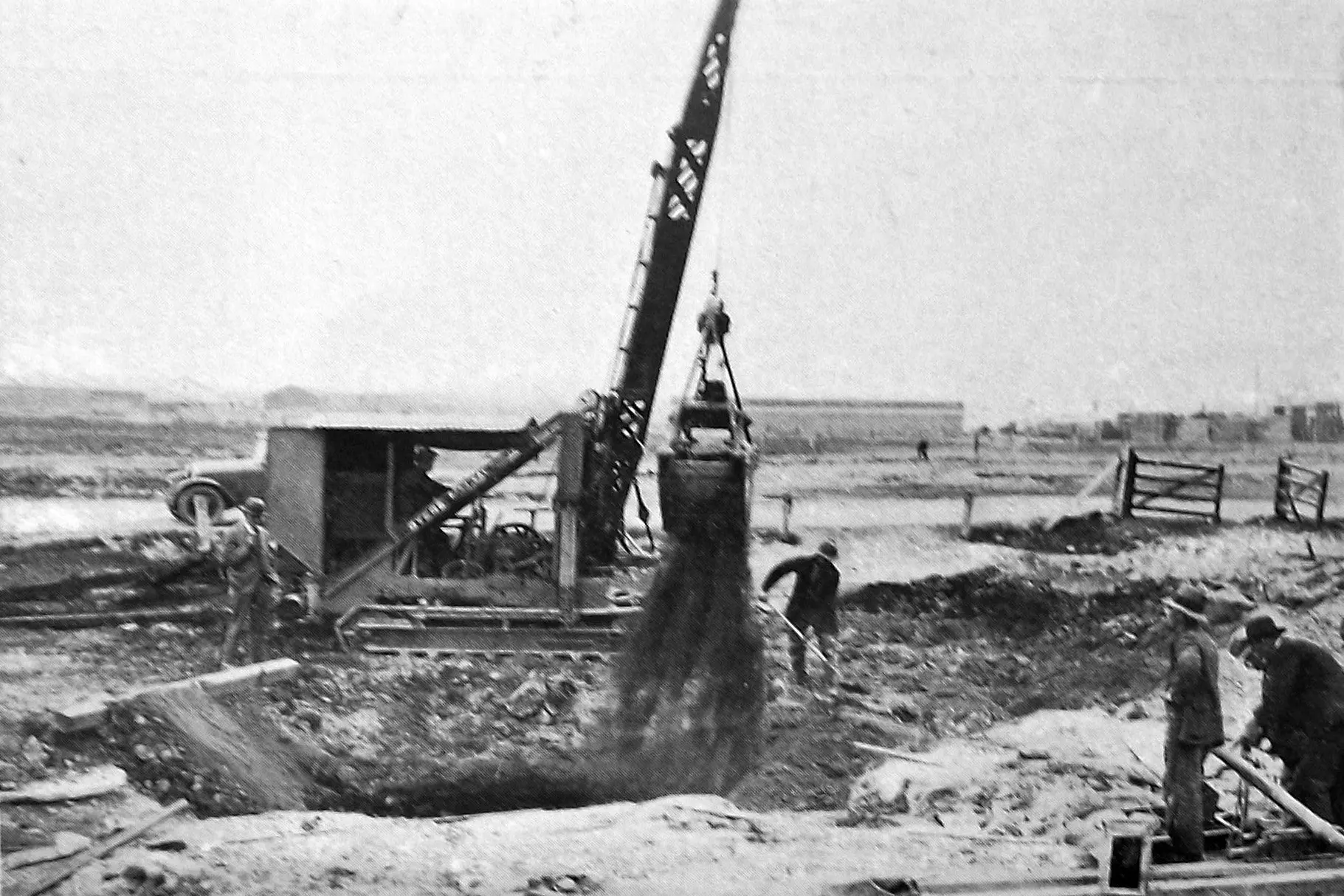 Dunedin Drainage Board workers fill in one of two tanks, 40 feet deep and 24ft in diameter at the top, which had never been used. It was estimated that 3300 loads of spoil would be required to fill them. Photo: <i>Otago Witness</i>, issue 3786, October 5, 1926, page 45
