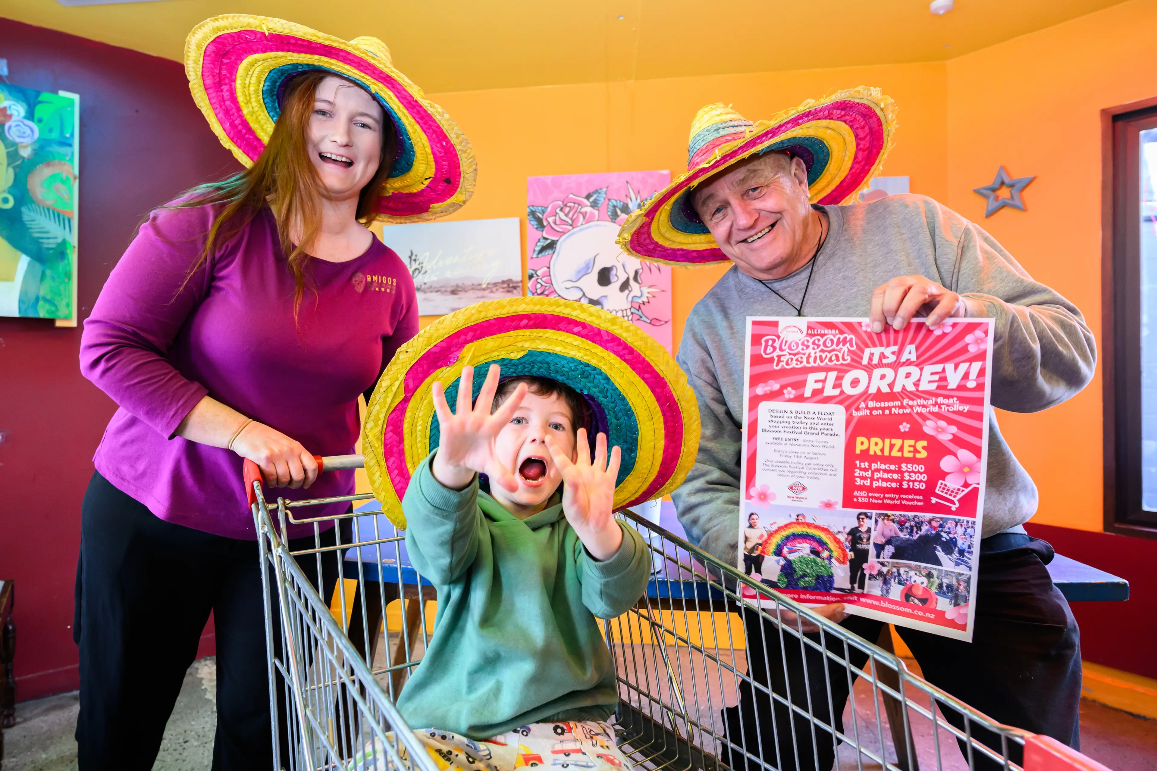Amigos Alexandra duty manager Sorcha Lee-Daly, Elijah Gilroy, 3, and Alexandra Blossom Festival event manager Martin McPherson are putting the call out for local businesses to enter a florry in this year\\'s Contact Alexandra Blossom Festival. Photo: Alexandra Blossom Festival/Shannon Thomson