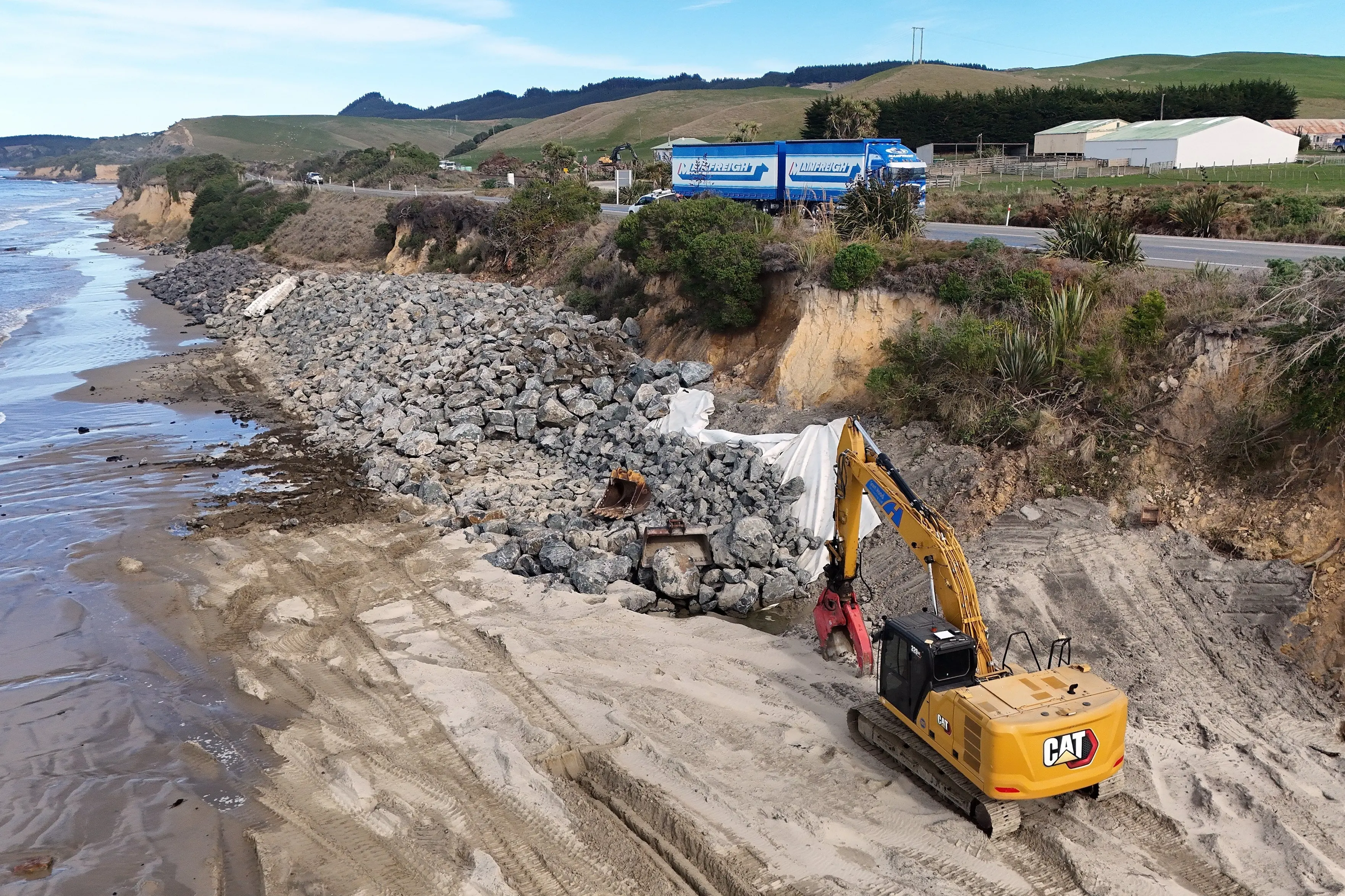 A digger places rocks to protect SH1 along Katiki Beach from coastal erosion. Photo: Stephen Jaquiery