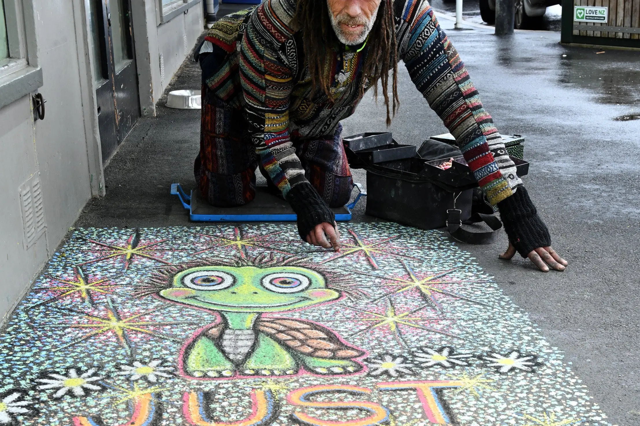 Chalk artist Tony Gillies puts the finishing touches on his art work on the footpath outside the Four Square St Clair, Thursday. Photo: Linda Robertson