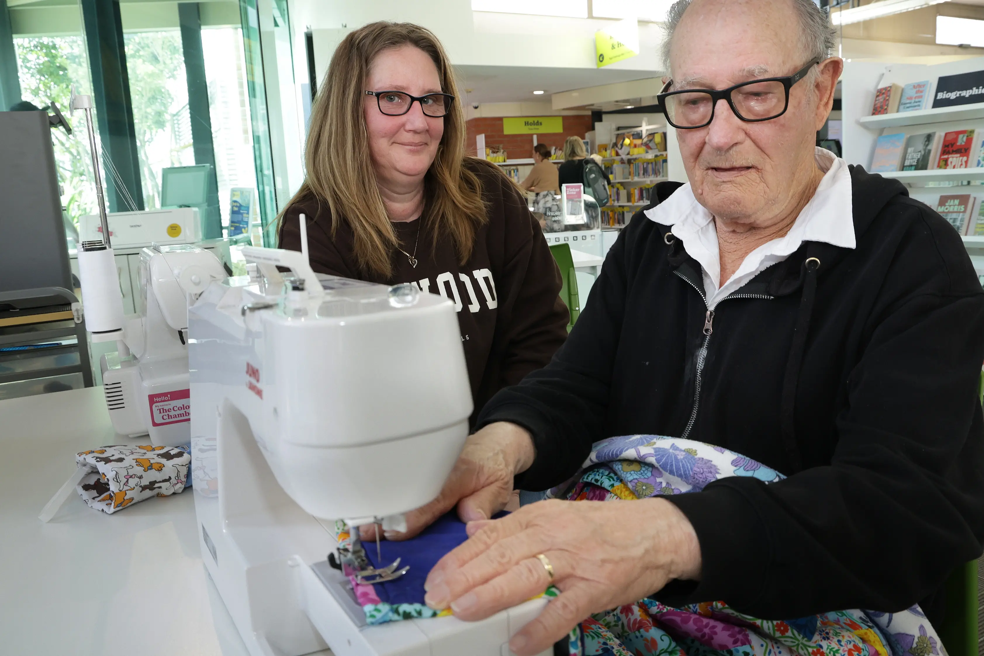 Nice job . . .Support worker Rachel Harris (left) helps Noel Gullery (81) to work on a sewing machine at the Rangiora Library. Photo: John Cosgrove