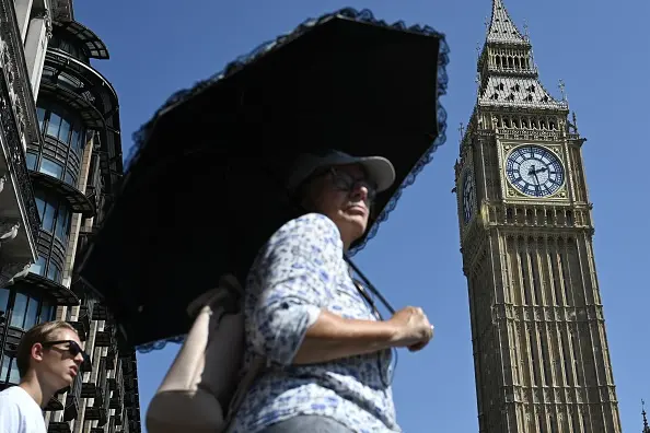 A woman uses an umbrella to shield herself from the hot sun in London. Photo: Anadolu via Getty Images