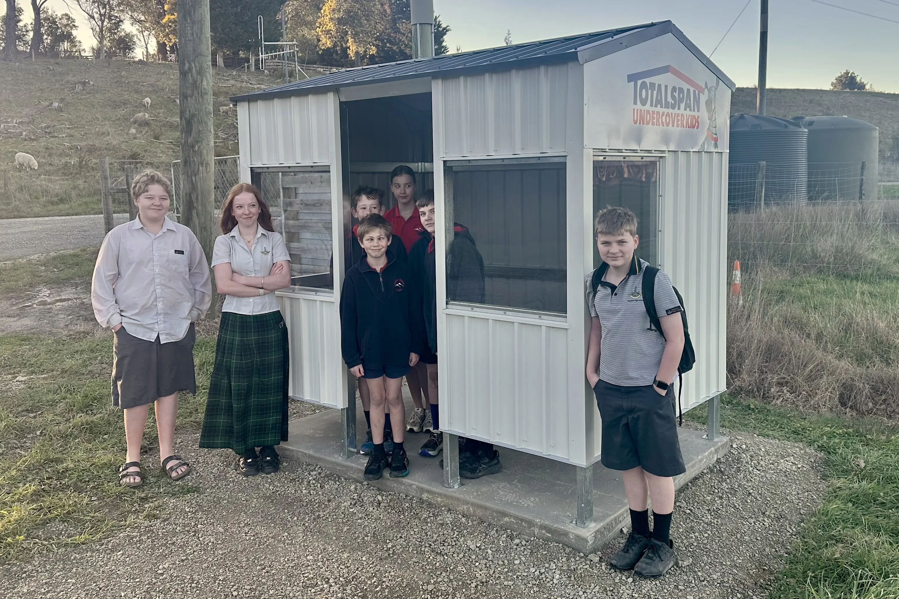 Happy and dry . . . North Loburn bus pupils are now able to shelter from the elements following a four-year campaign to get a bus shelter. Photo: Catherine Sellin.