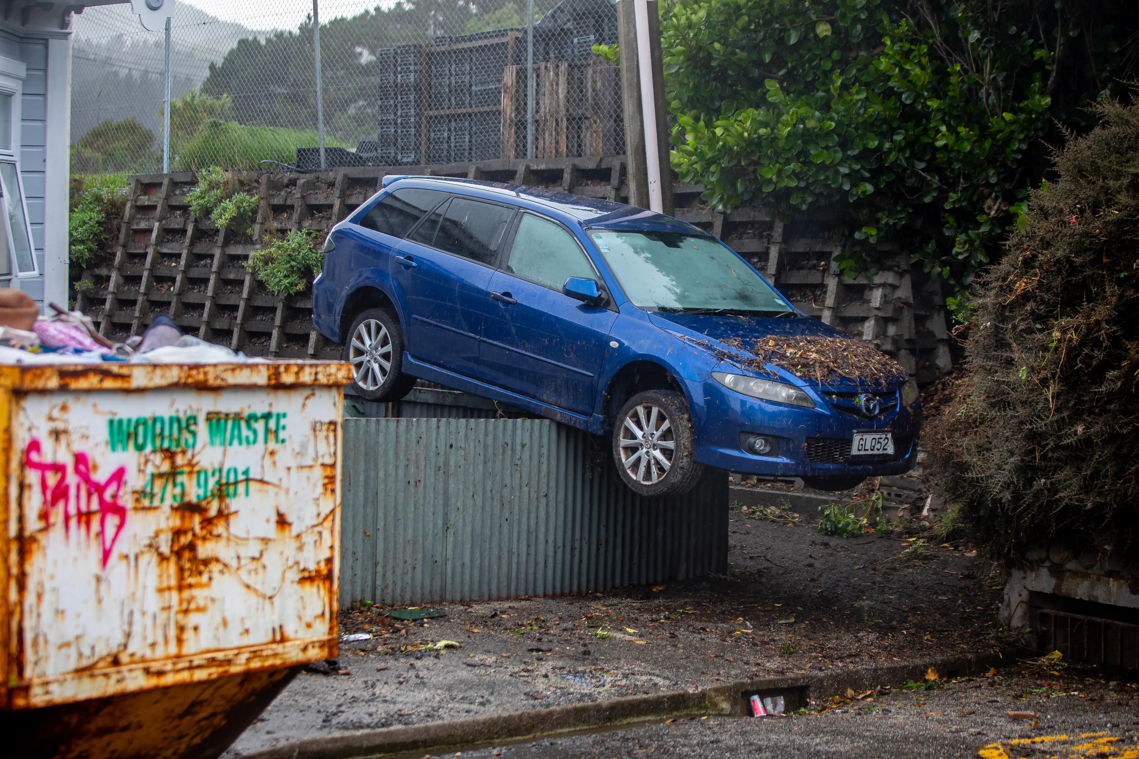 A car carried by floodwaters landed on top of a chest-high fence after torrential rain in Wellington. Photo: RNZ / Mark Papalii