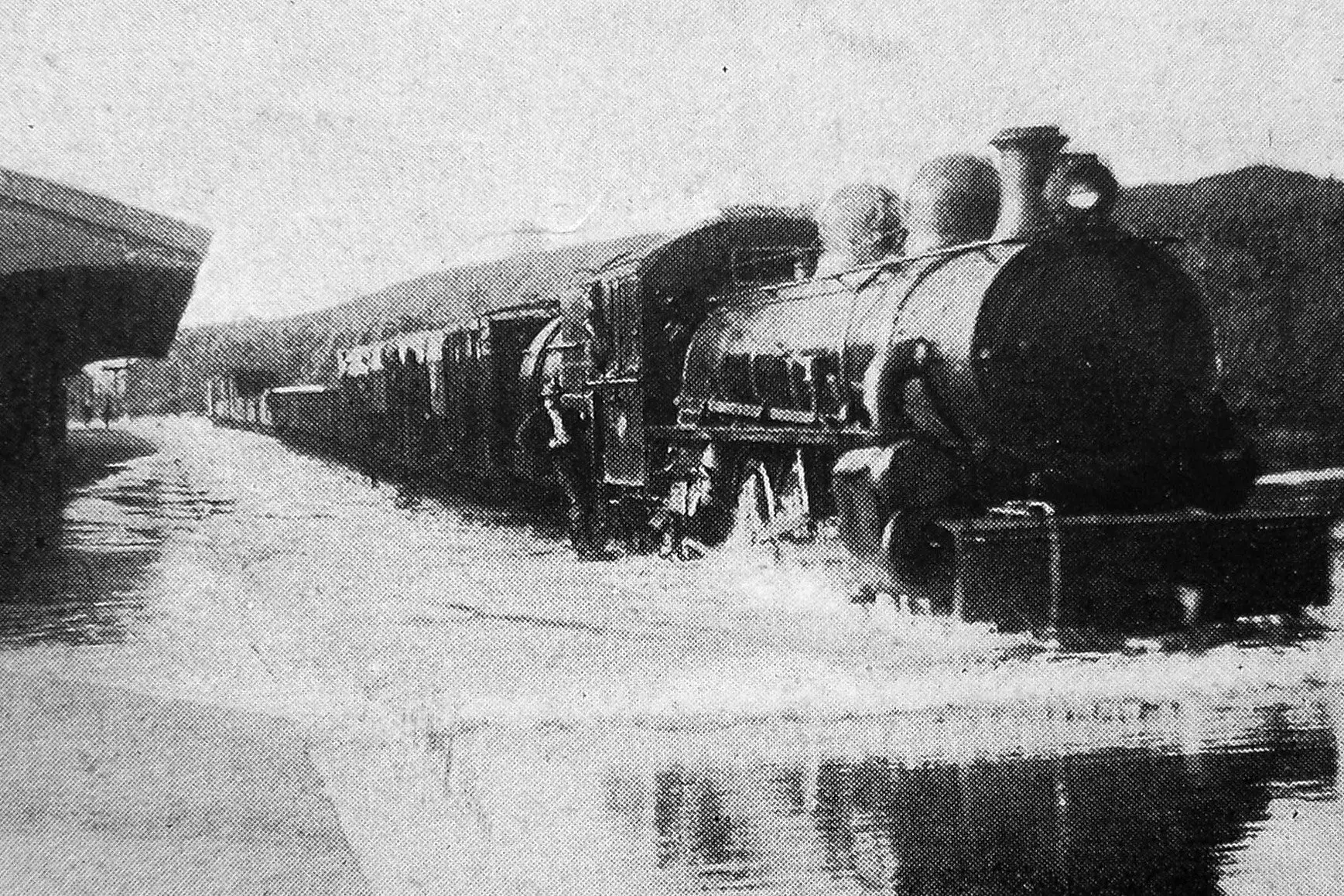 A goods train creates a bow wave as it passes Mercer station, Waikato during a flood. Photo: <i>Otago Witness</i>, issue 3790, November 2, 1926, page 48
