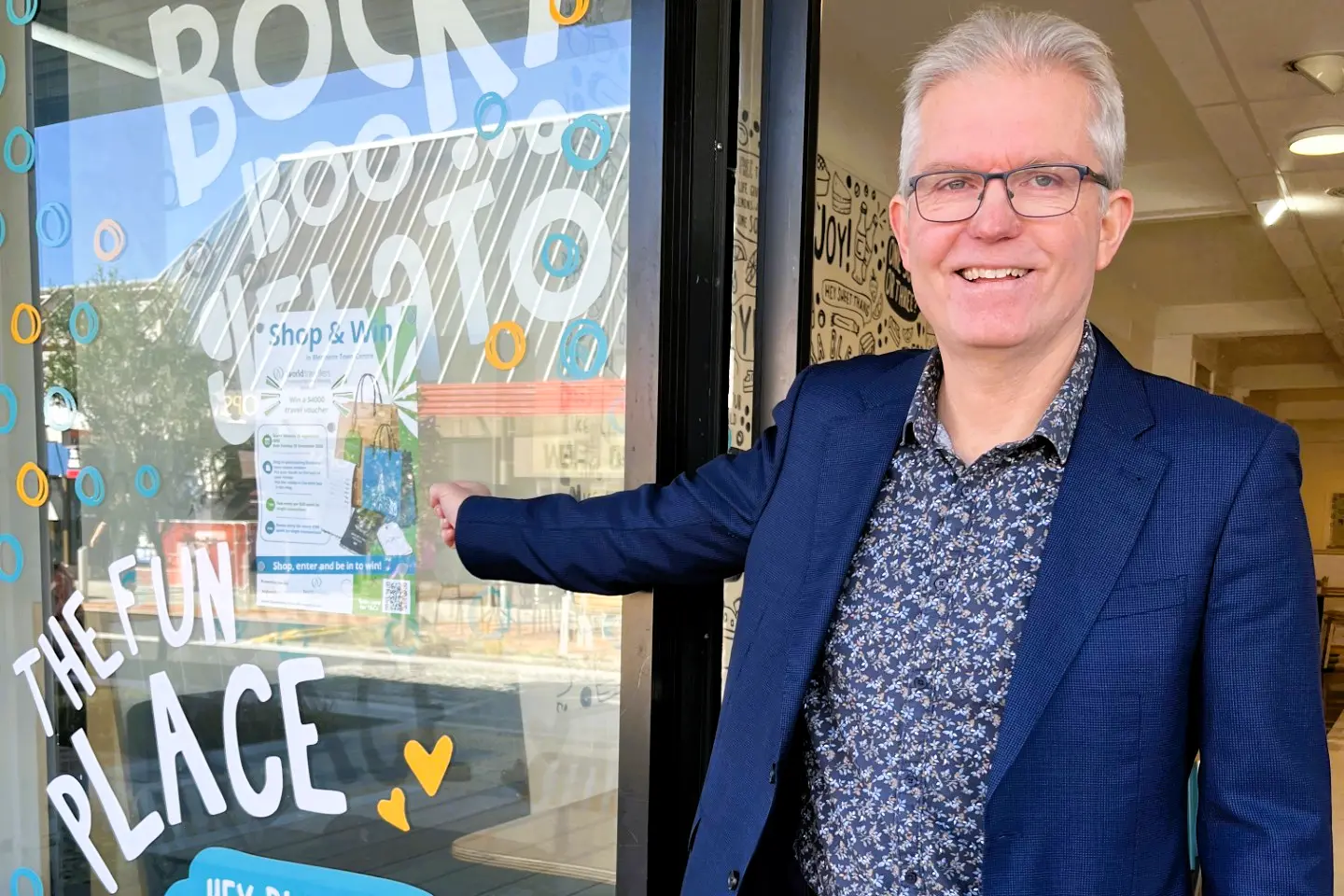 Business Trust Marlborough manager Brian Dawson points out a poster in the window of a town centre retailer taking part in the new Shop and Win promotion. Photo: Cathie Bell
