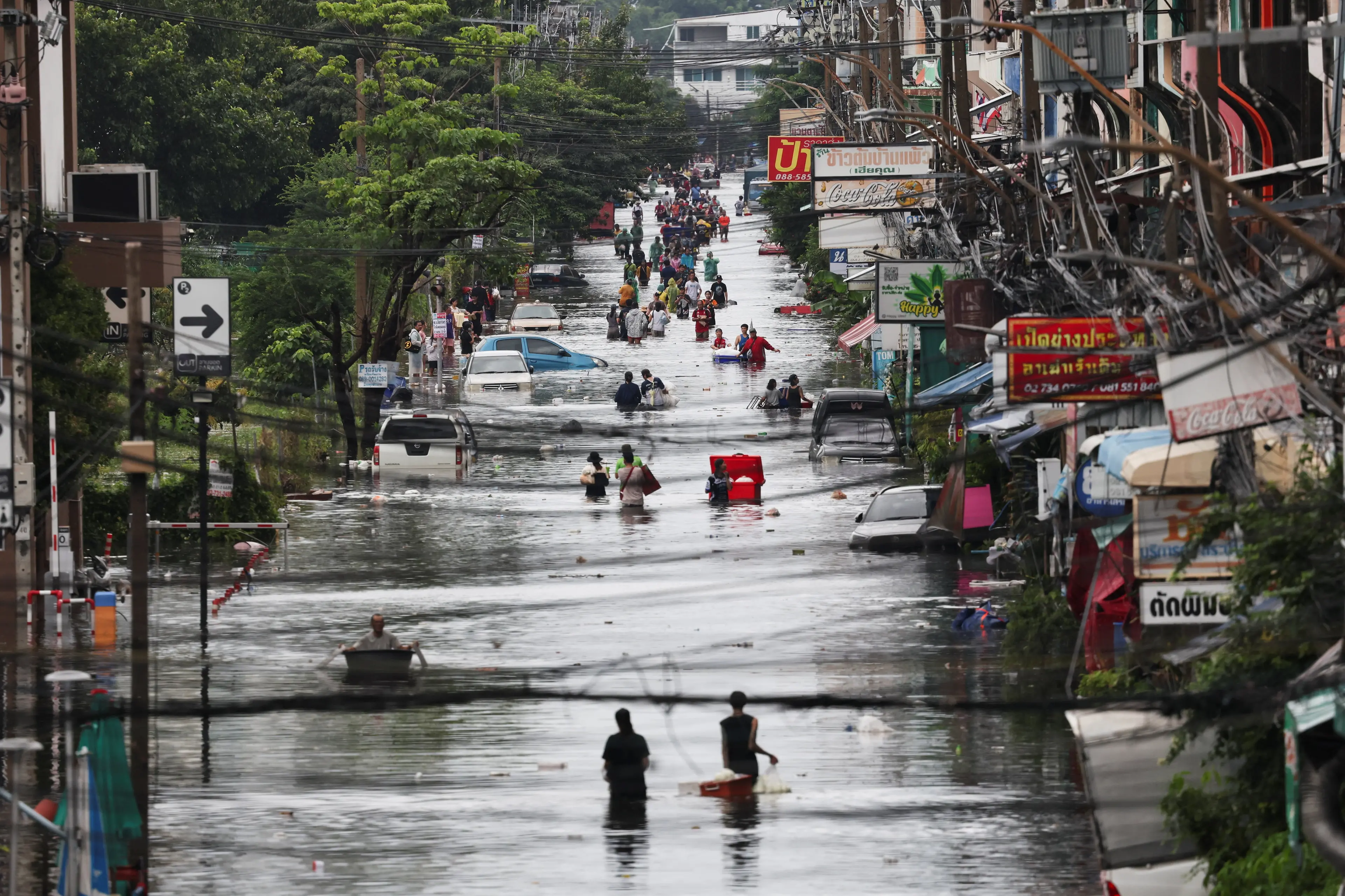 <p>People wade through a flooded area, in Bangkok, Thailand. Photo: Reuters </p>\\n