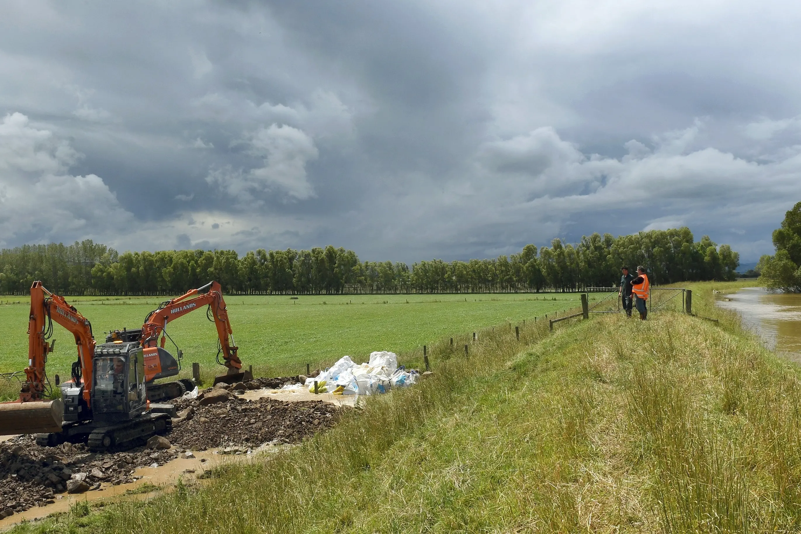 Workers use diggers and truckloads of rock to stem a breach in the Taieri flood bank near Otokia Rd during a high river flow in 2021. Photo: Stephen Jaquiery