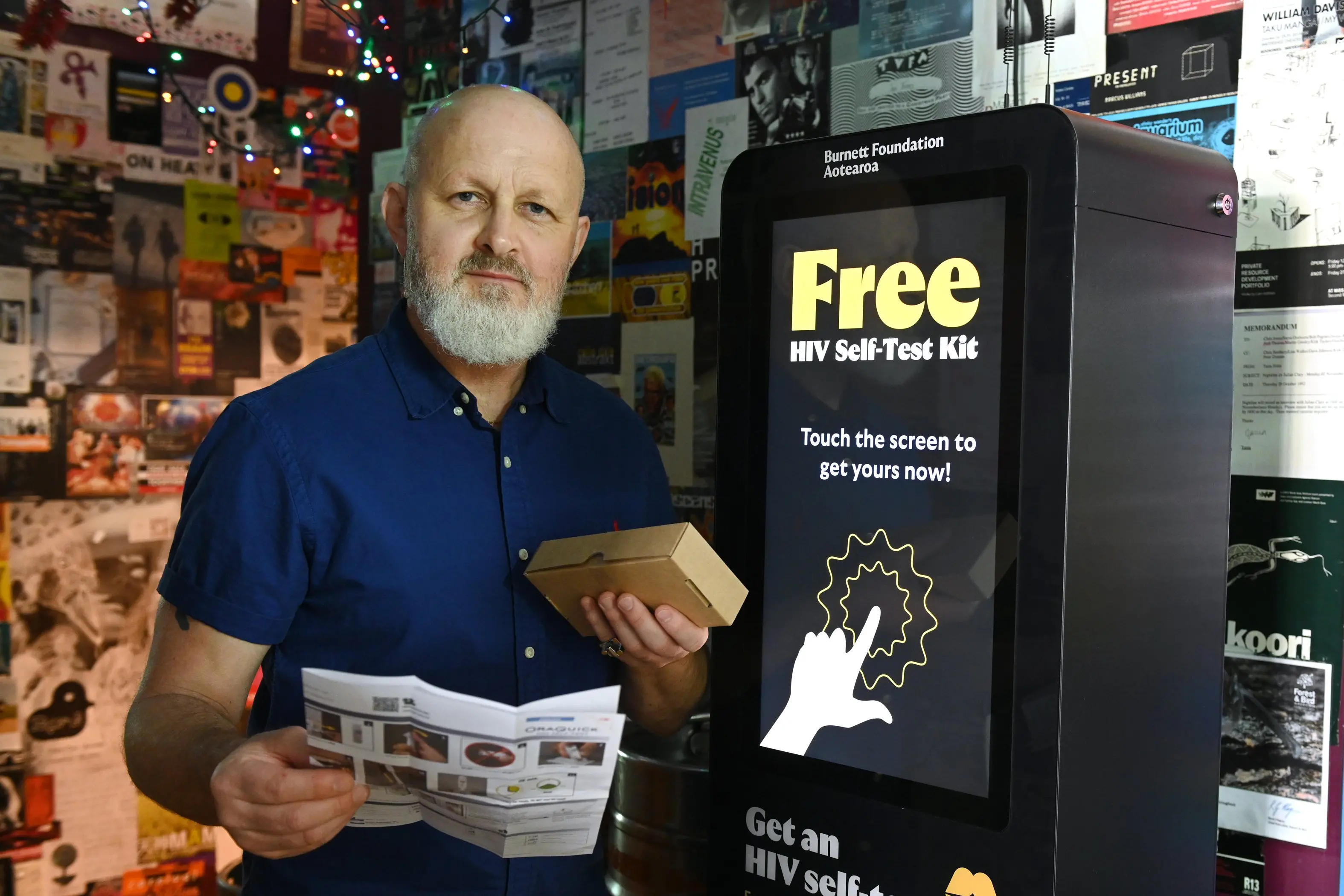 Woof! owner Josh Thomas holds an HIV home testing kit from a Burnett Foundation vending machine at the Dunedin bar. Photo: Linda Robertson