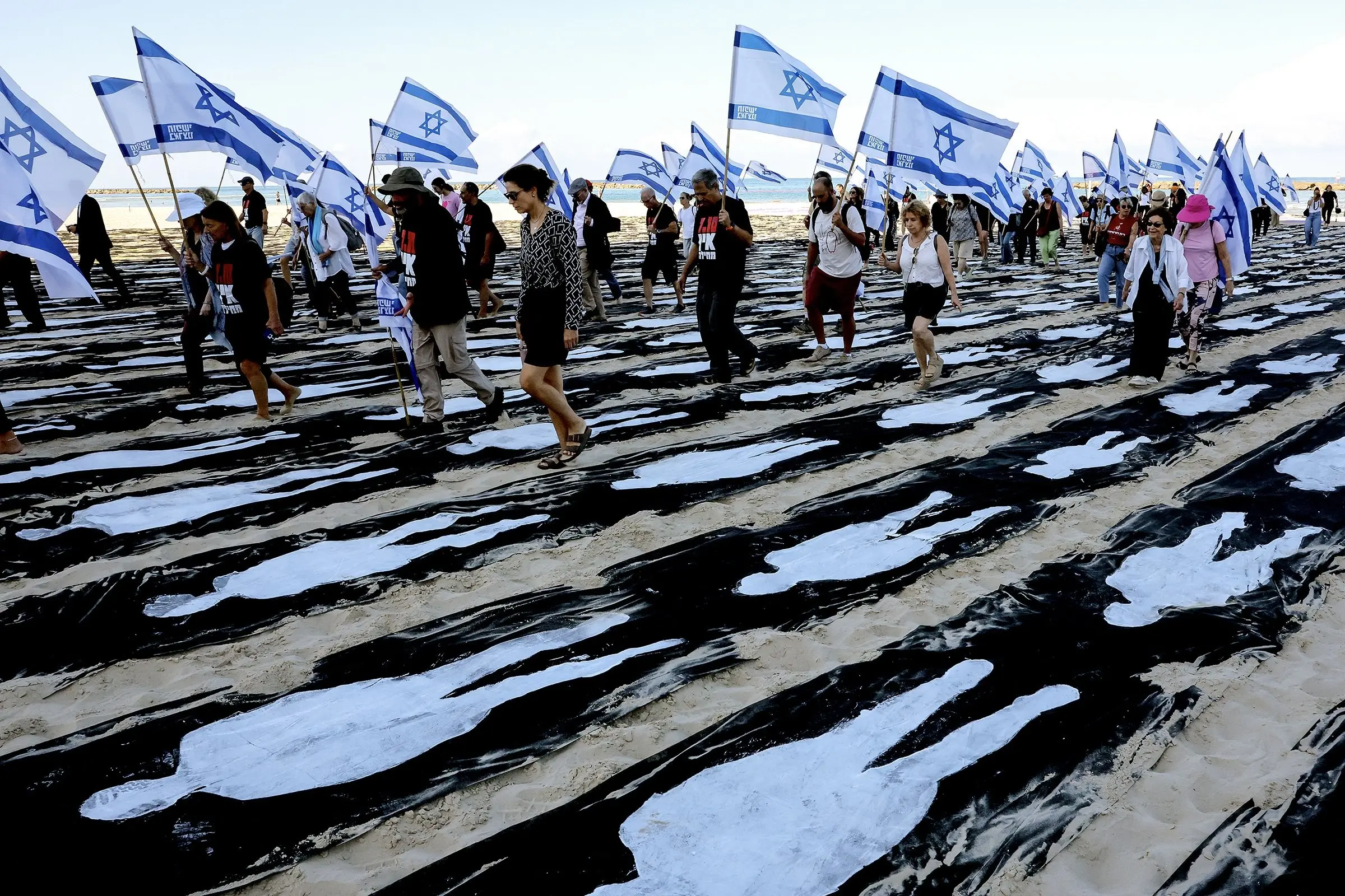 People carrying Israeli flags walk through a commemorative installation set up on the beach in Tel Aviv to mark the third anniversary of Hamas\\'s Oct. 7 attack on Israel. Photo: Getty Images