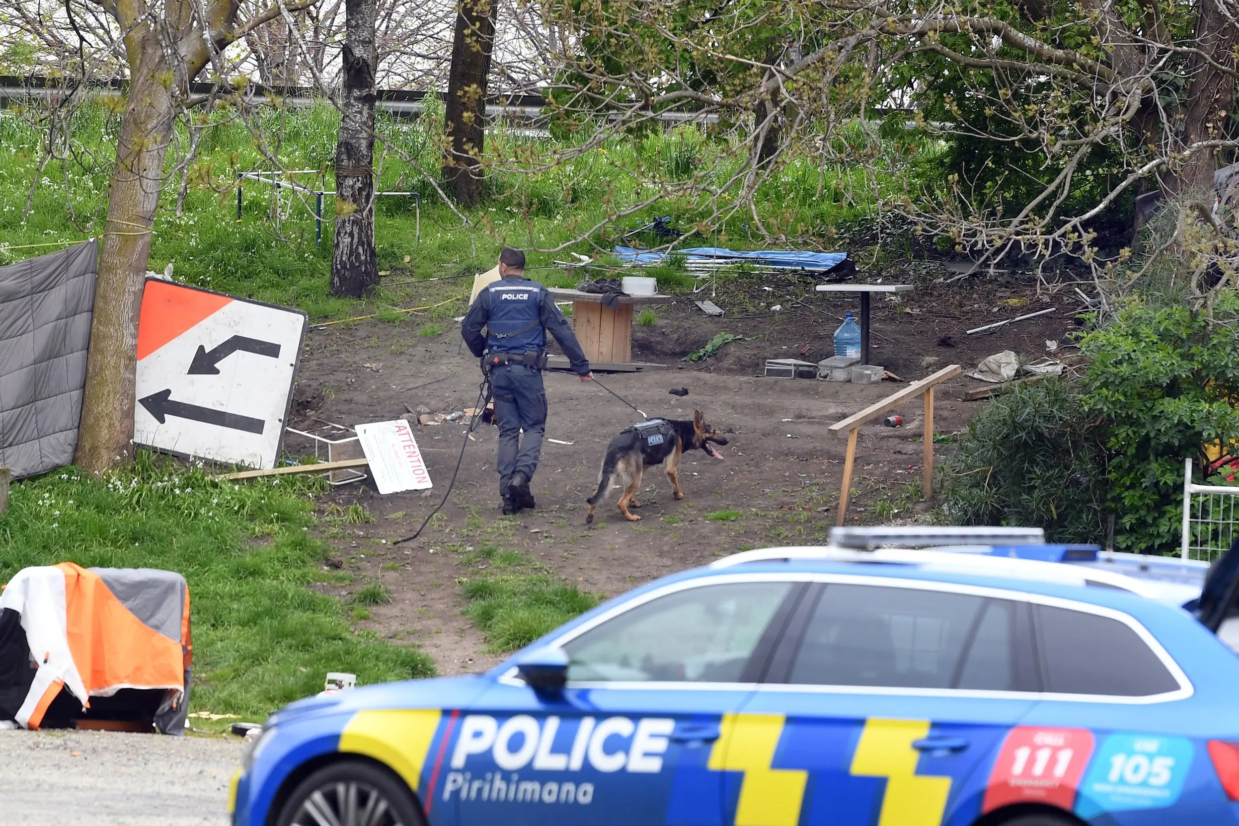 Police with a tracking dog search the tent city near the Kensington Tavern for a fleeing motorcyclist on Wednesday. Photo: Stephen Jaquiery