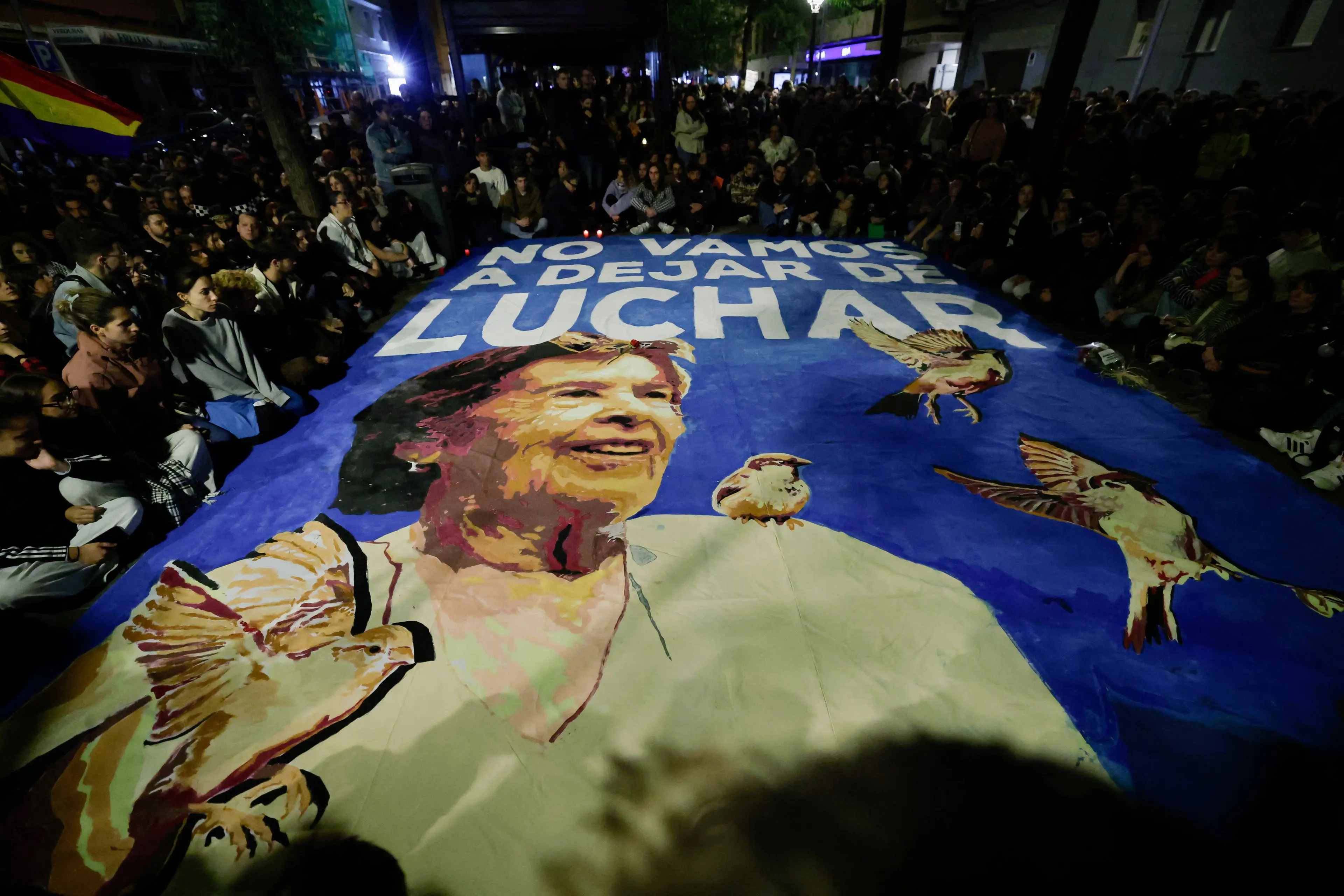 Protesters sit around a banner with a portrait of Maricarmen Abascal, who died before she was allowed to move back to her home. Photo: Reuters