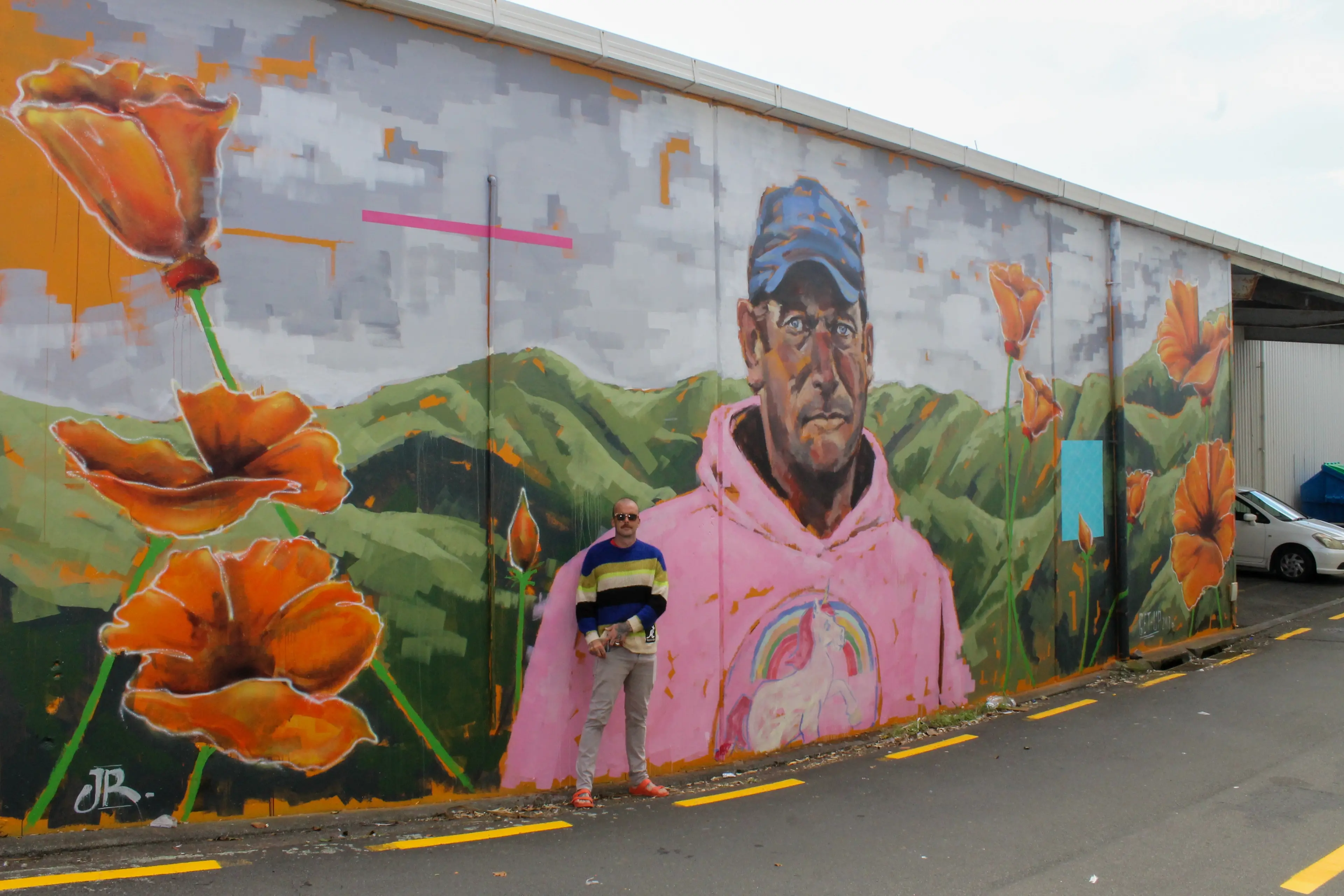Joseph Rowntree stands in front of a mural painted on the Rock Shop Building in New Playmouth as part of GetUp Festival in Taranaki in March 2026. Photo: Supplied