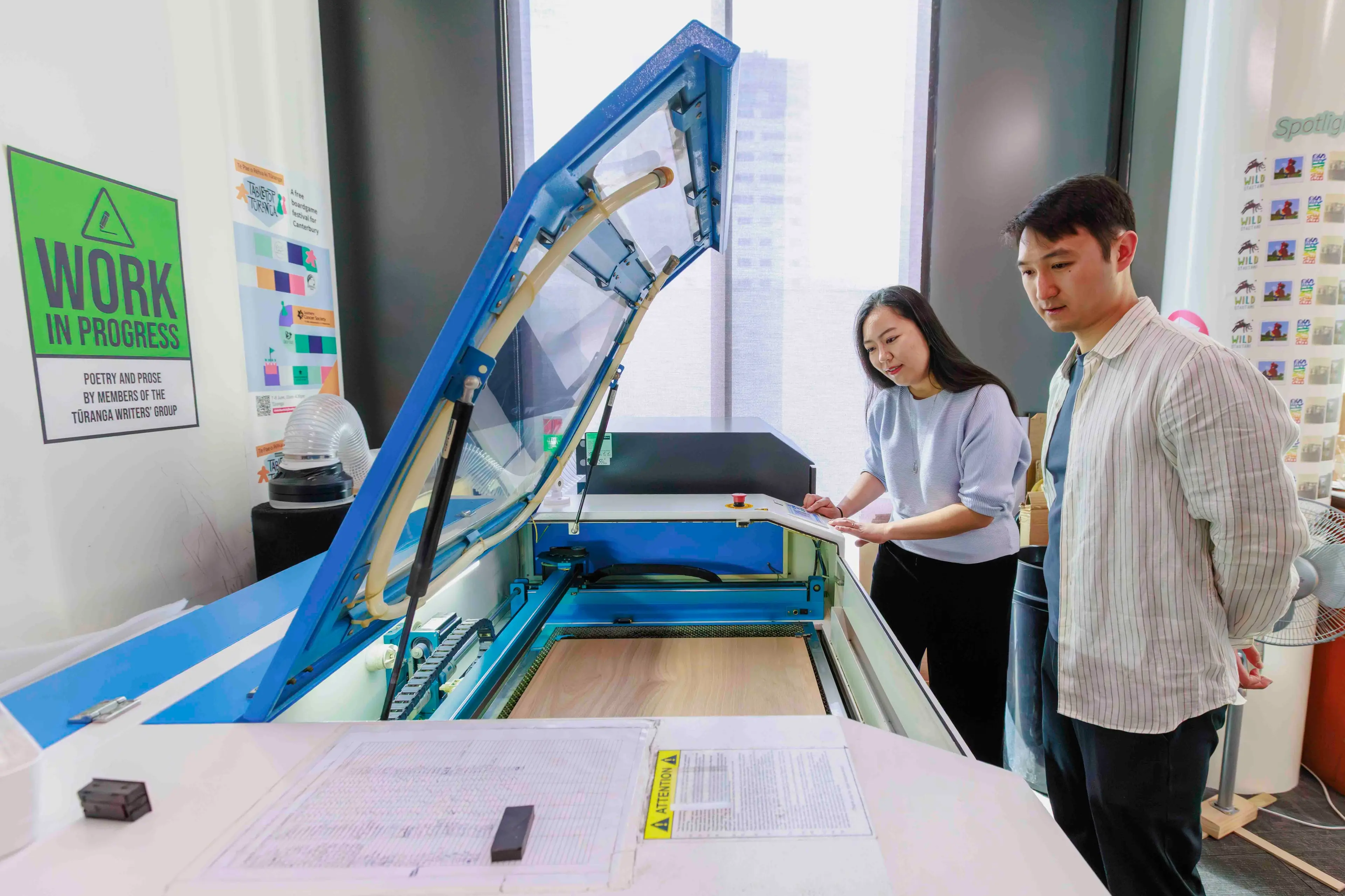 Minami Yoshida and Chris Wang using the laser cutter in T\\u016Branga\\u2019s Creative Space to create parts of their board game Cubeli. Photo: Supplied