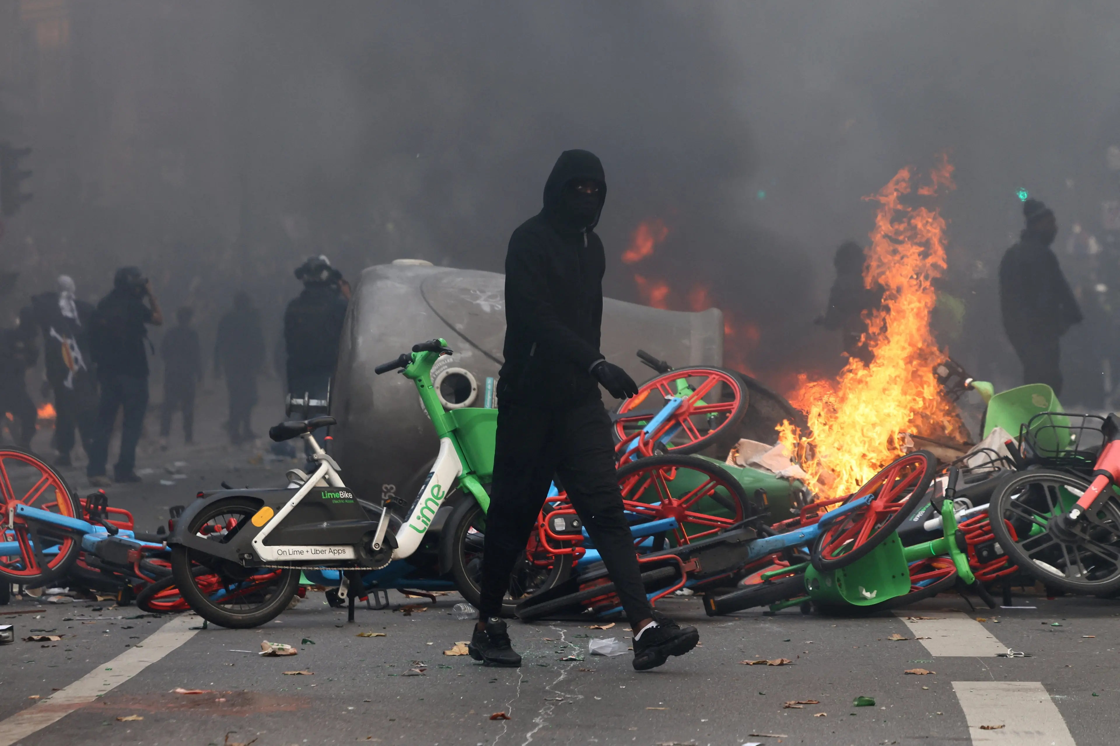 A masked protester walks past burning bicycles in Paris amid ongoing unrest in France. Photo: Reuters
