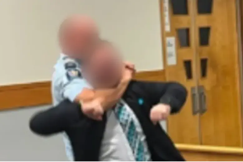 A photo of the lawyer in a headlock was shared in the group chat. RNZ has blurred the faces of the lawyer and police officer. Photo: Supplied