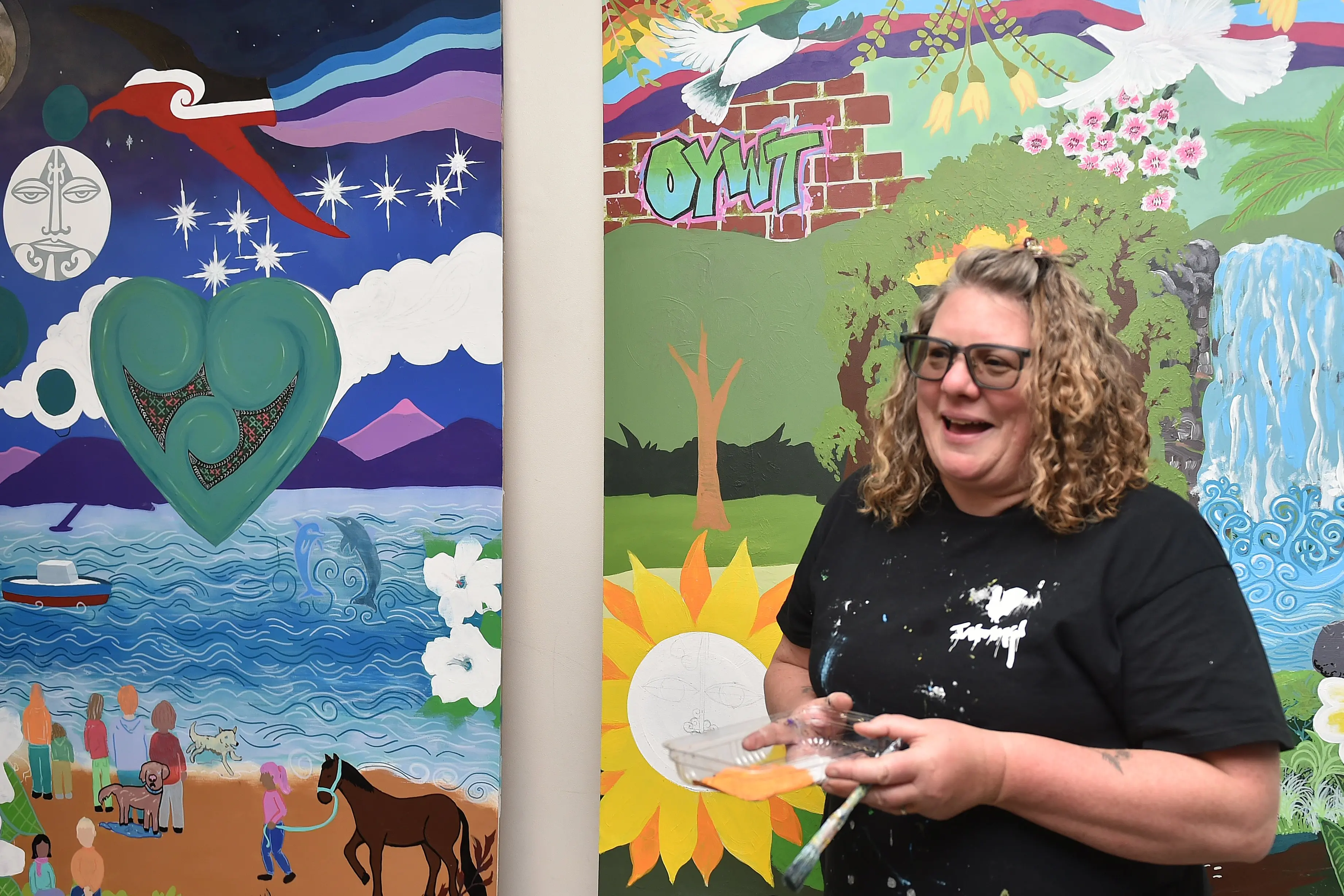 Artist Claire Rye shows off the mural at the Otago Youth Wellness Trust 30th anniversary celebrations.\\r