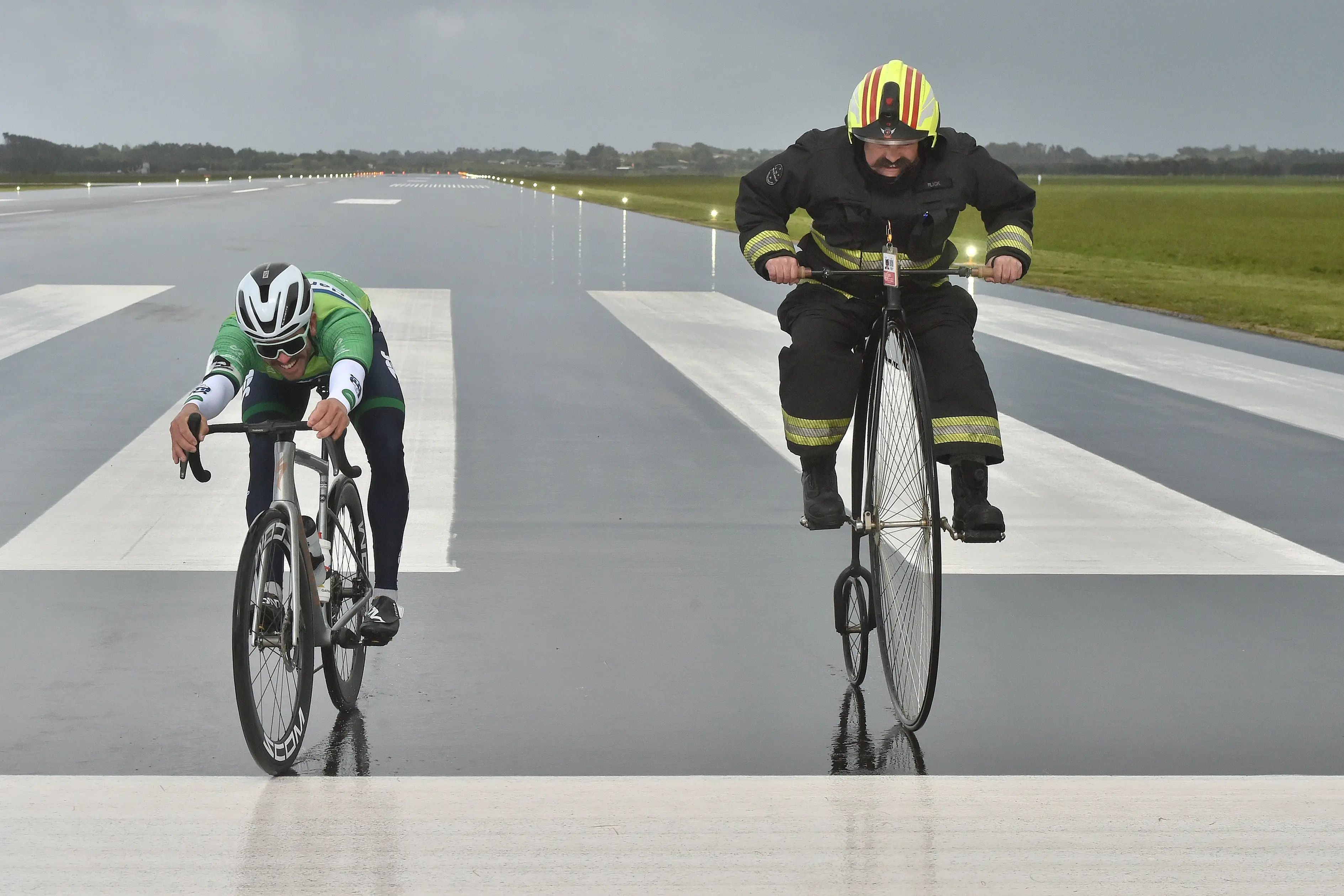 Tour of Southland sprinter Nick Kergozou (left) and Invercargill Airport senior firefighter Jed Martin cross the line in their runway grudge race on Friday morning. Photo: Gregor Richardson