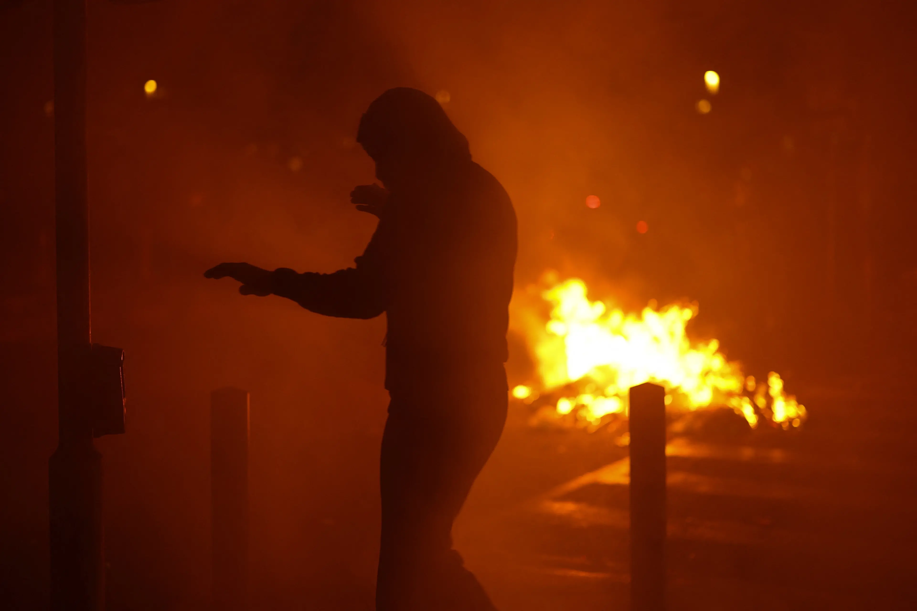 A protester walks amid smoke, with fire burning in the background, during a demonstration organised by labour unions as part of nationwide protests against the cost of living and rising fuel prices, in Marseille, France. Photo: Reuters